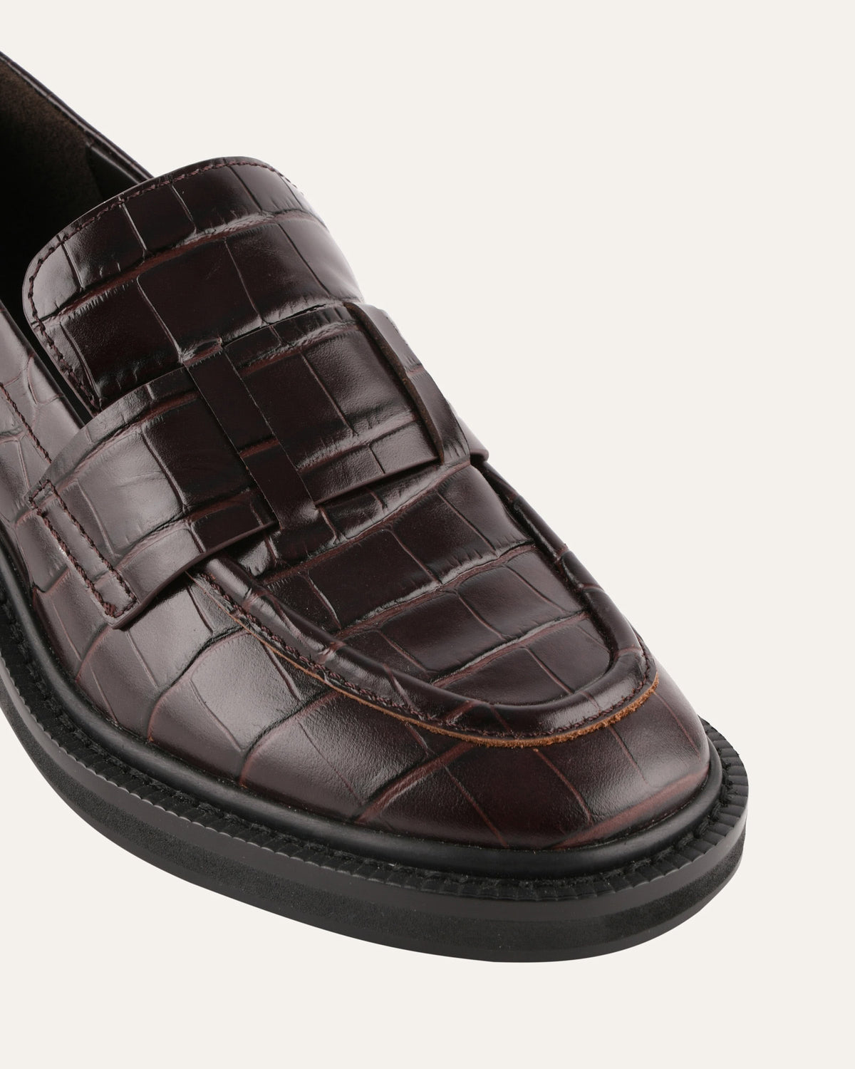 Brown crocodile-patterned loafer shoe on a light gray background