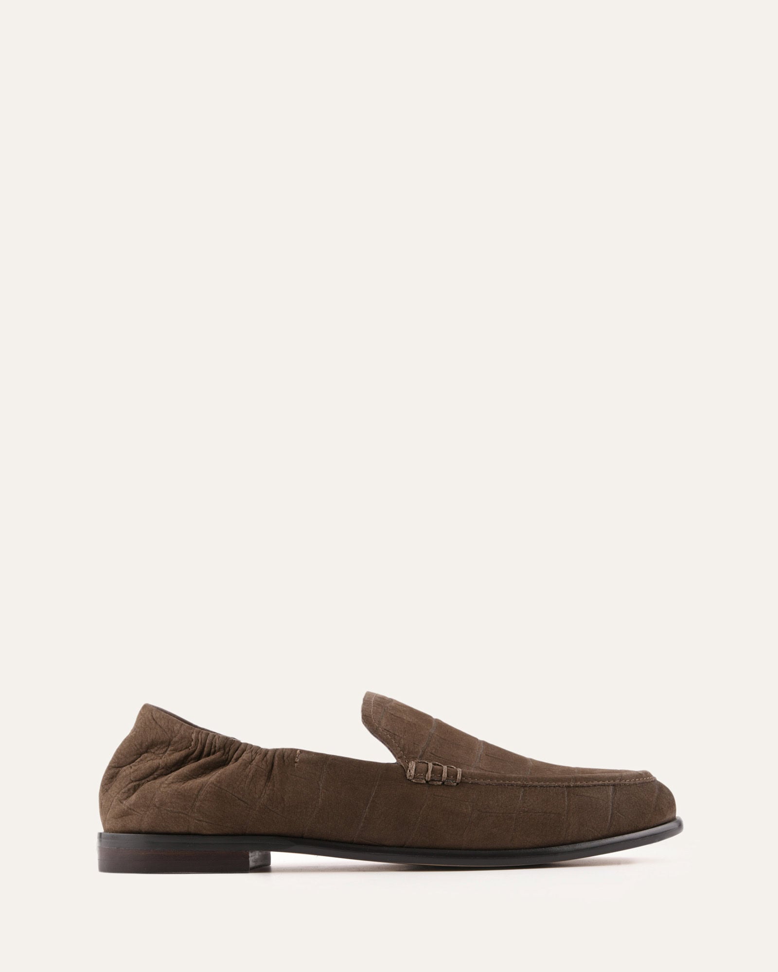 Brown loafer shoe on a light beige background