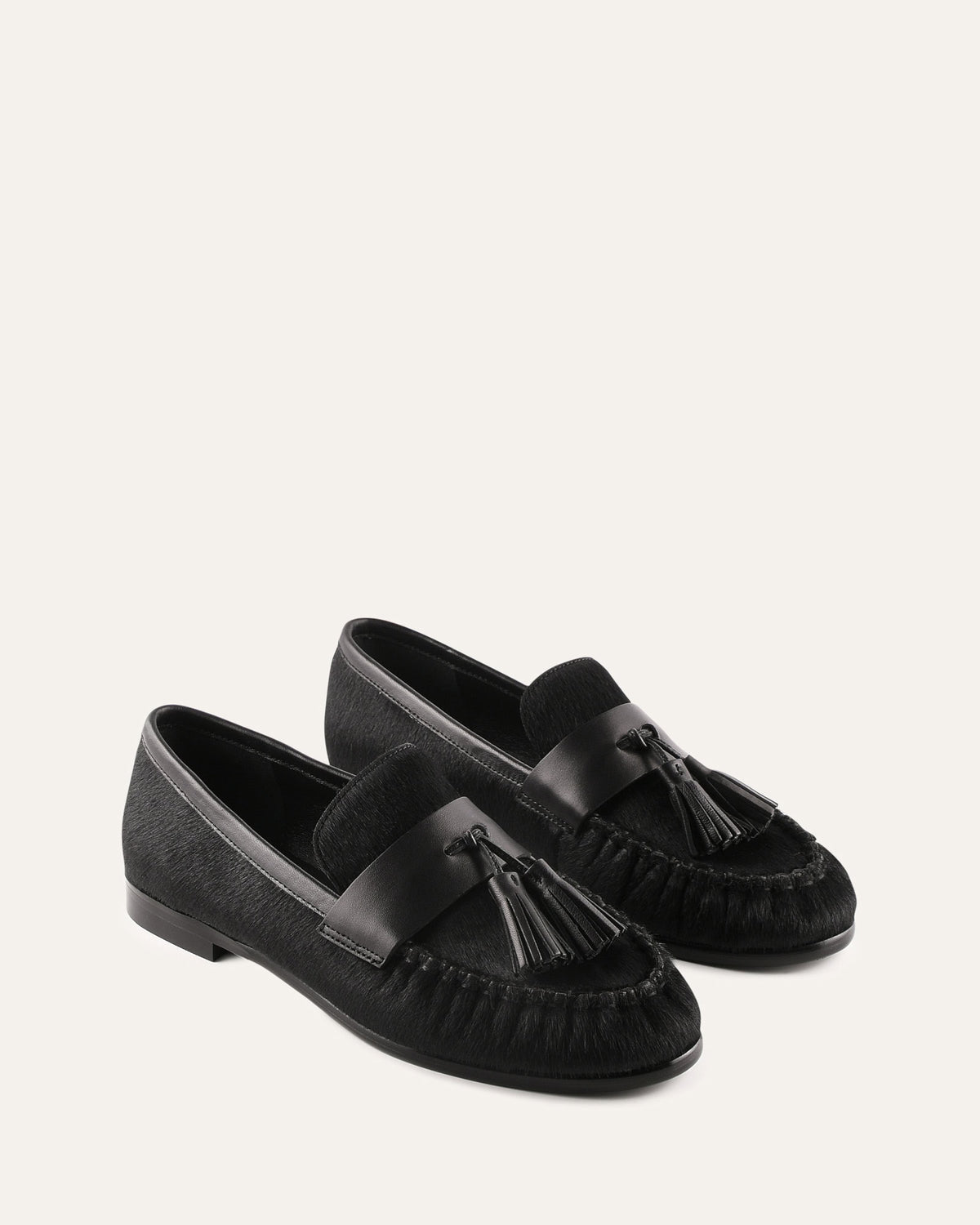 Black loafers with tassels on a light gray background