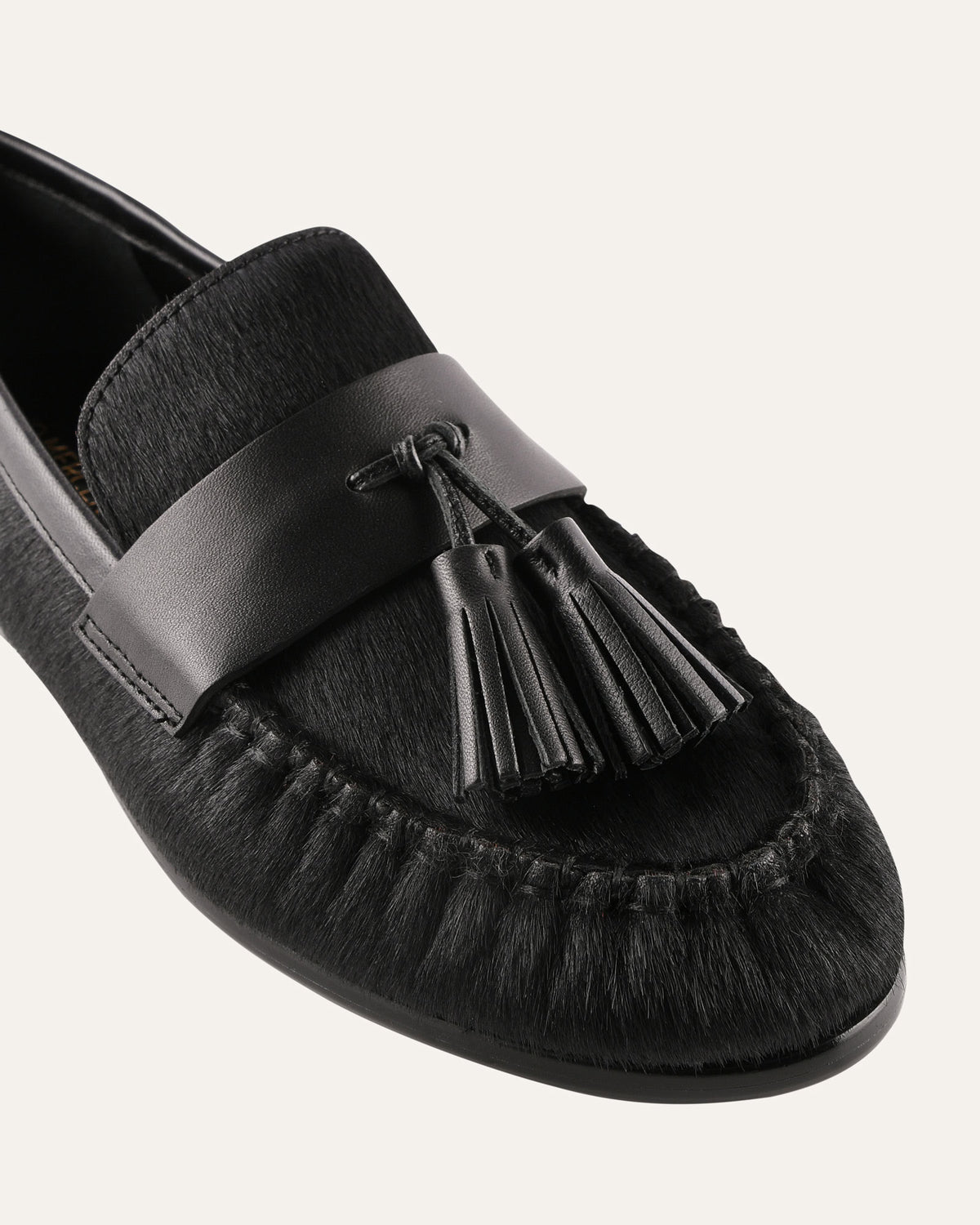 Black loafer shoe with tassel on a white background