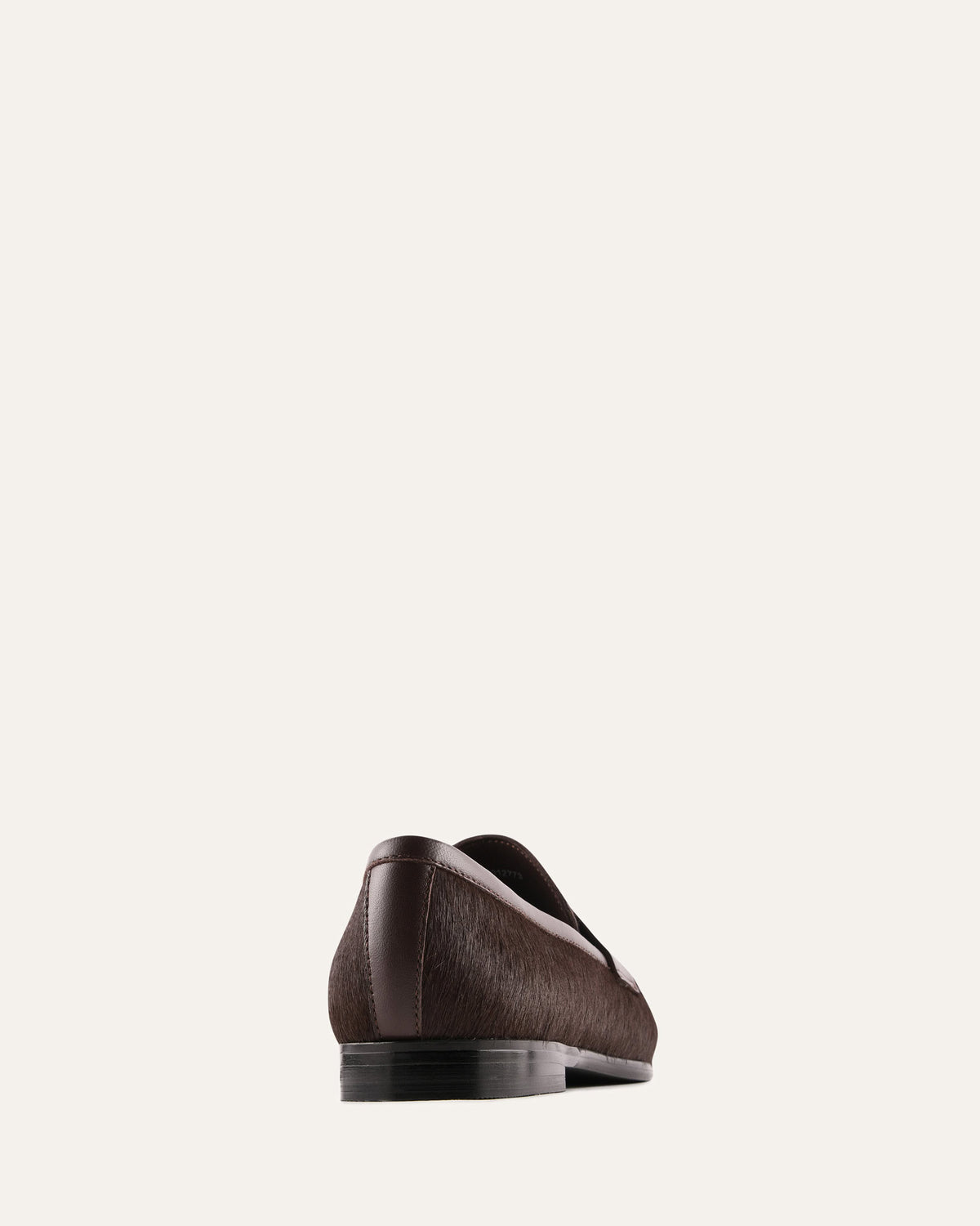 Brown leather loafer on a light beige background
