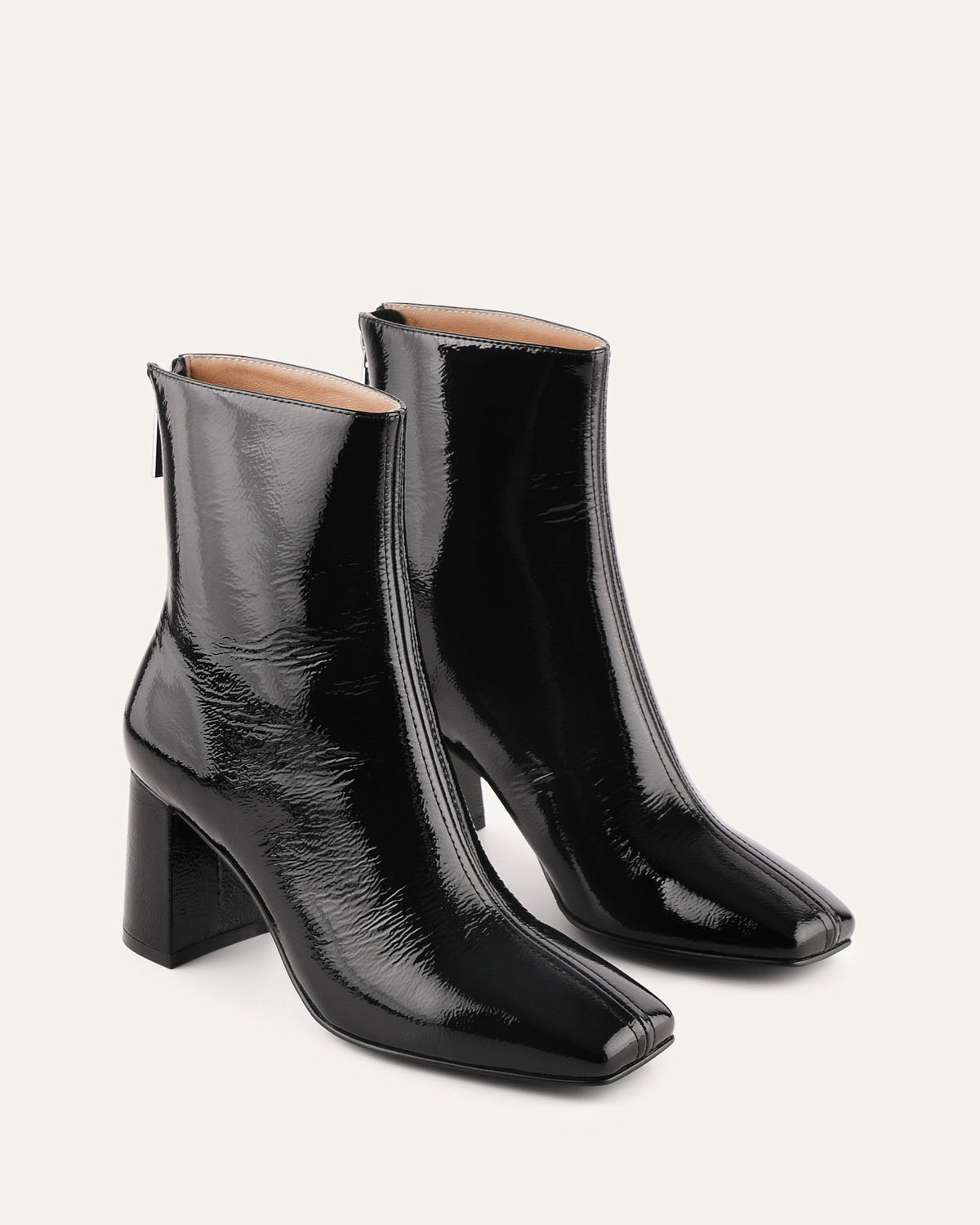 Black patent leather ankle boots on a light gray background