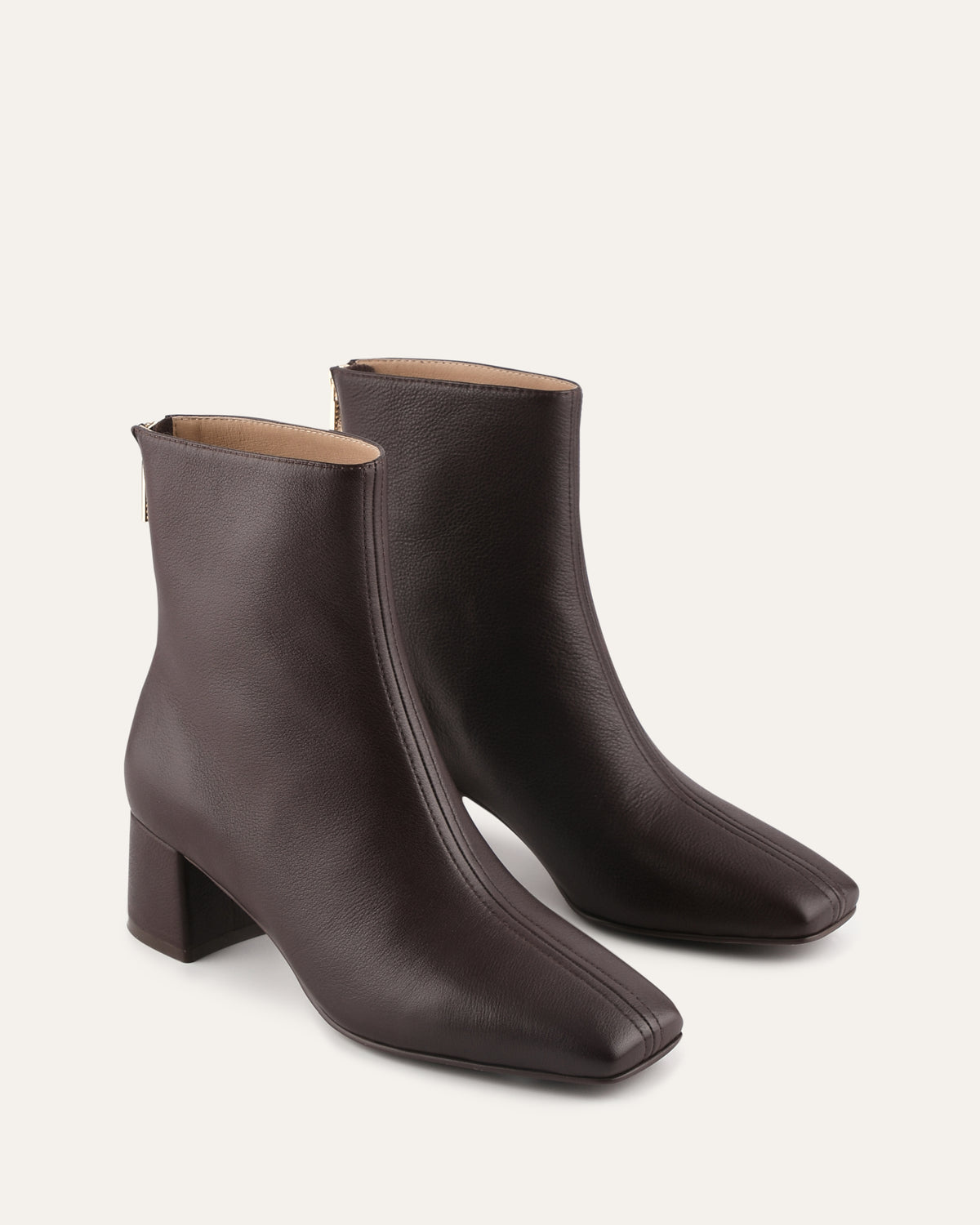 Pair of brown ankle boots on a light beige background