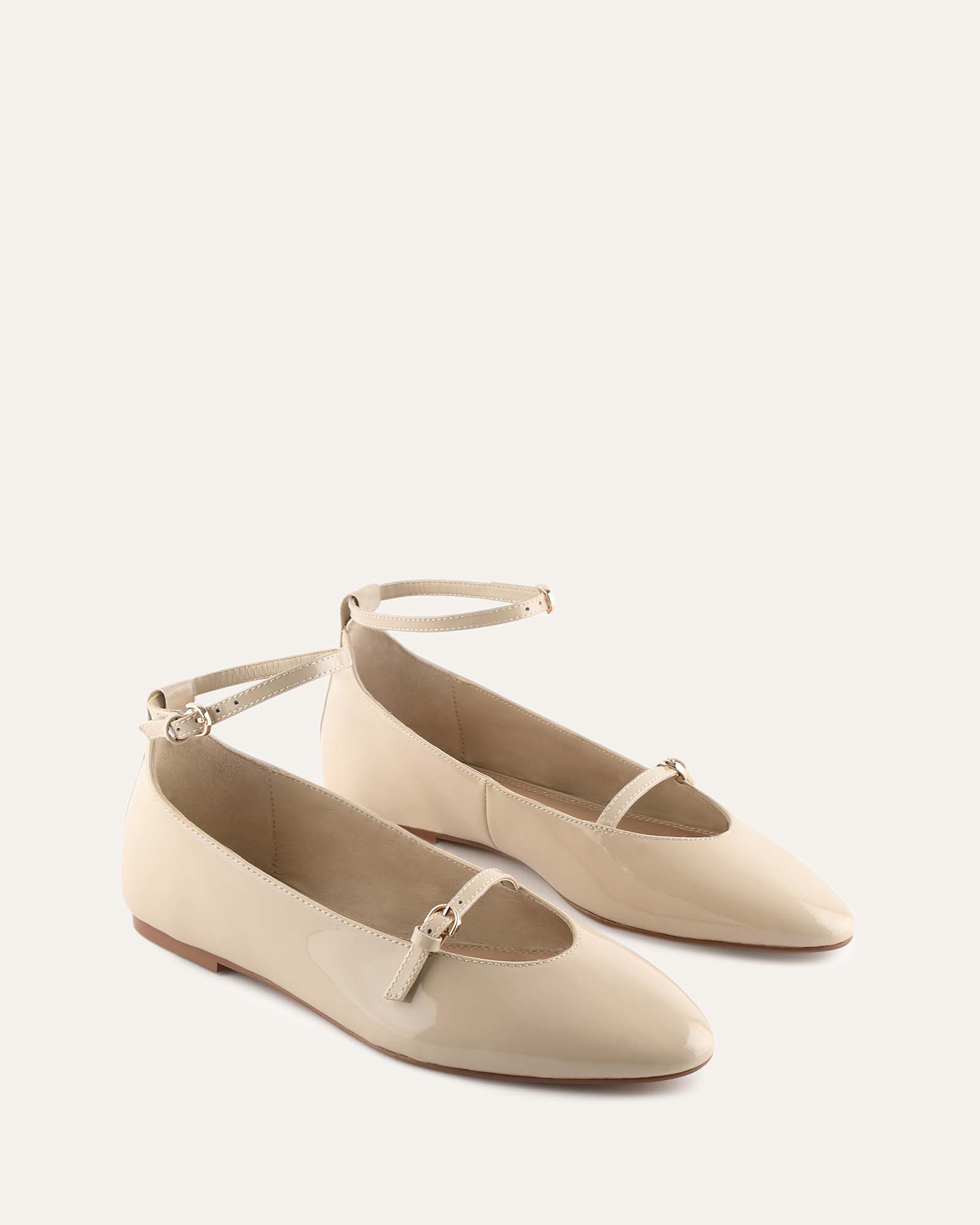 Beige flat shoe with ankle strap on a light gray background