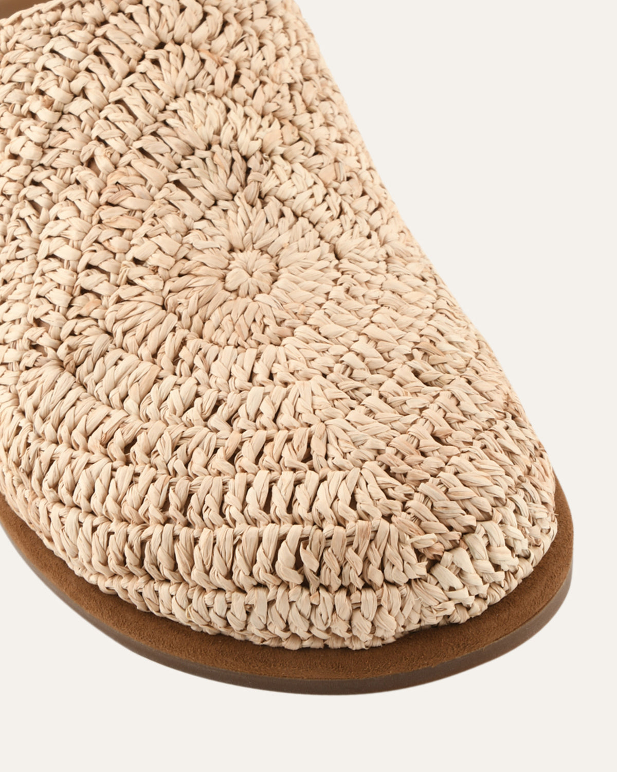 Close-up of a woven beige slipper with a brown sole on a white background