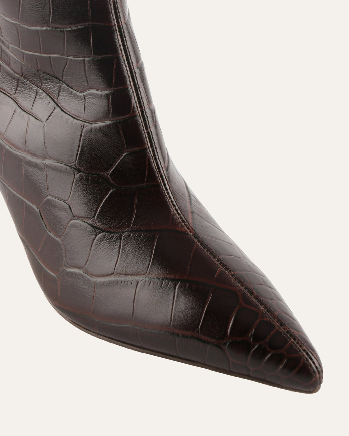 Close-up of a brown crocodile-patterned high-heeled shoe on a white background