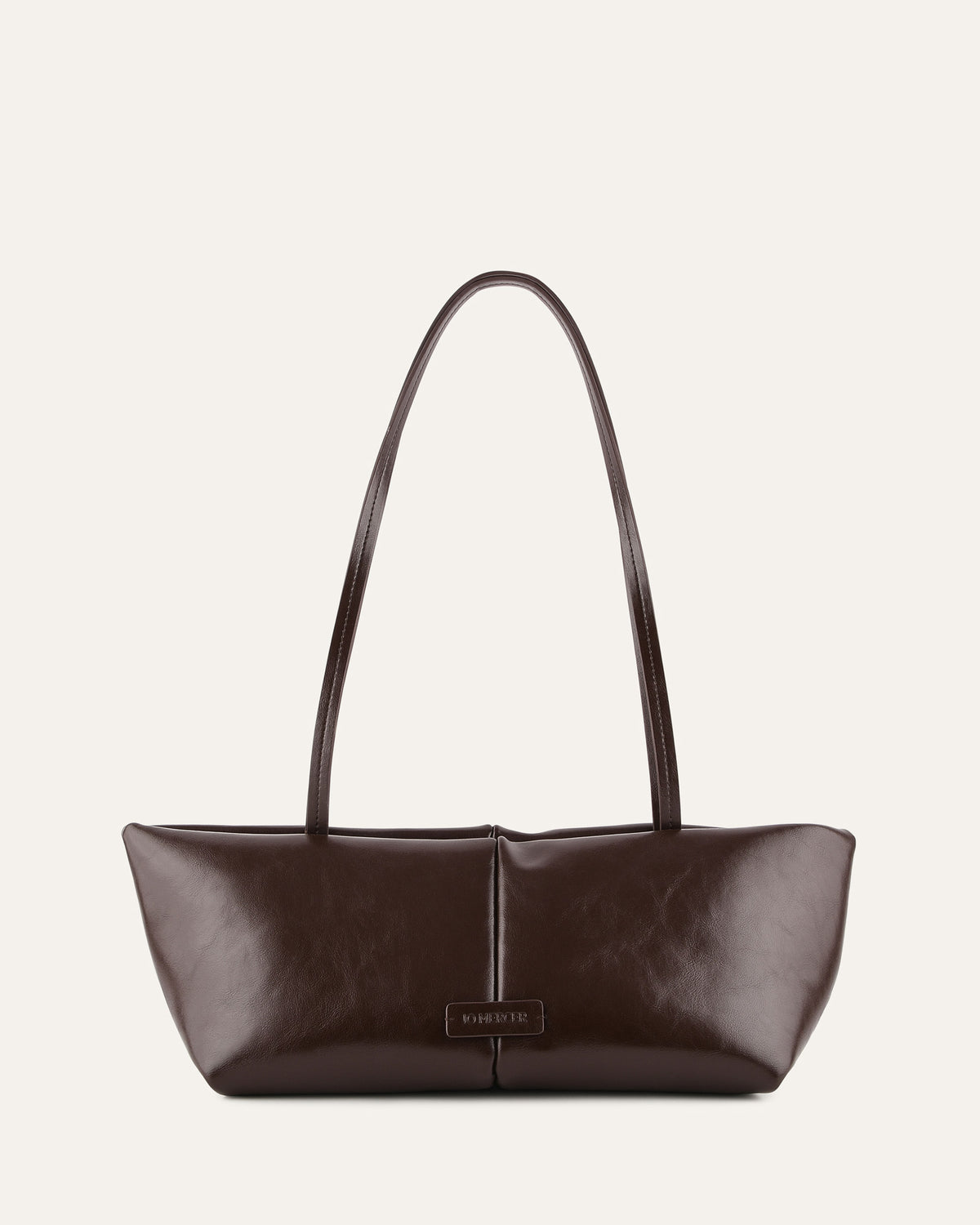 Brown leather handbag with a visible brand label on a light beige background