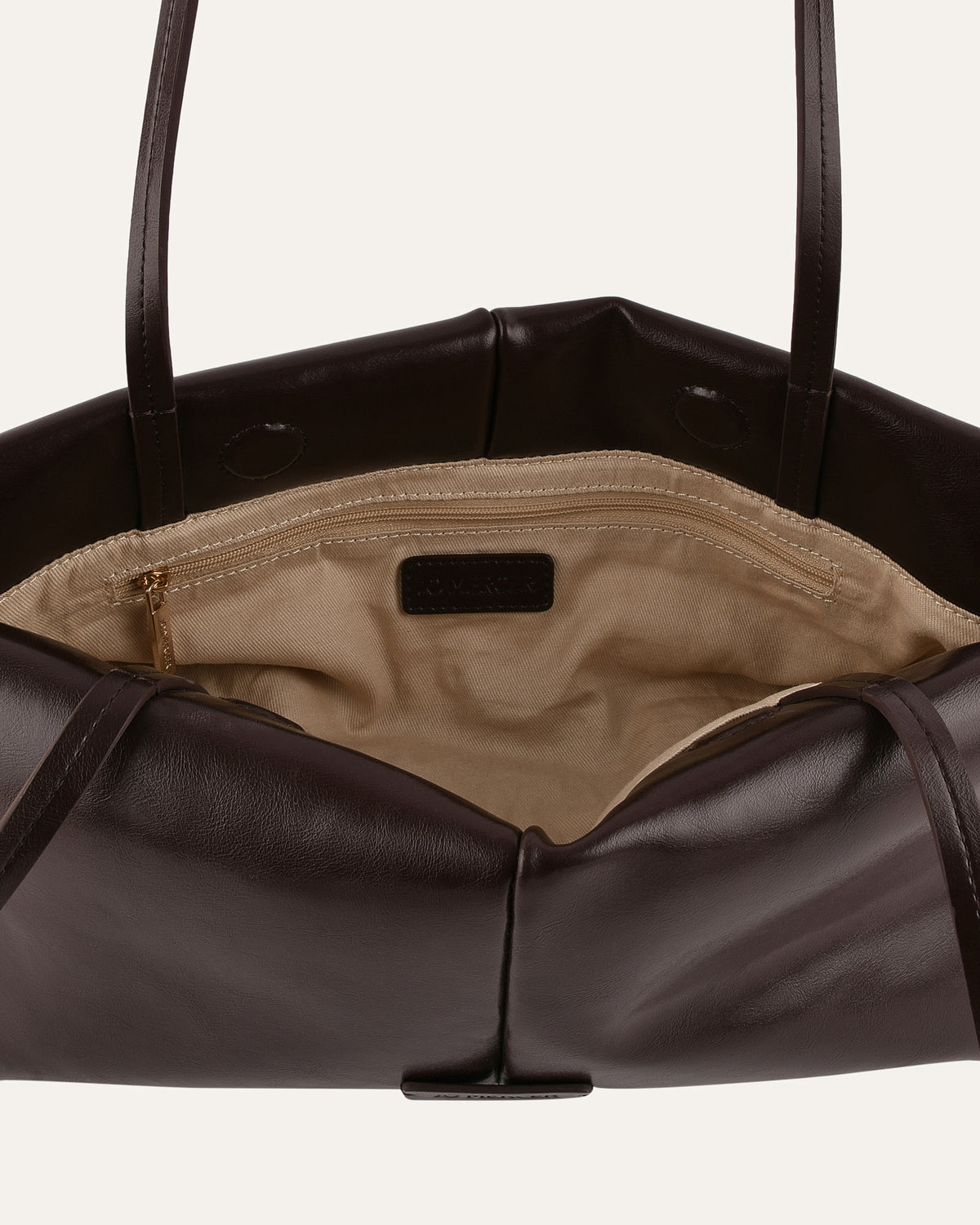 Brown leather handbag with beige interior on a light gray background
