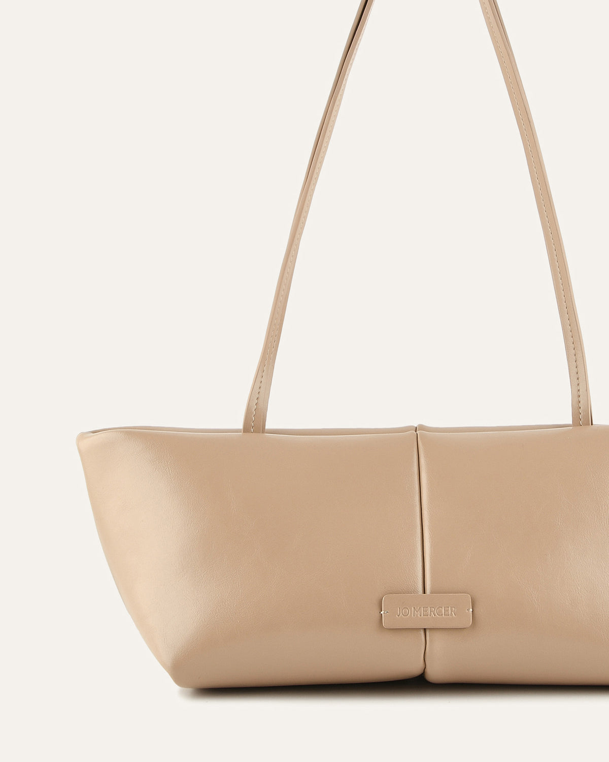 Beige handbag with a visible brand label on a light beige background