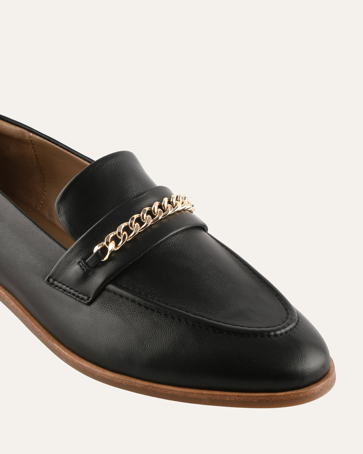 Black loafer with gold chain detail on a white background