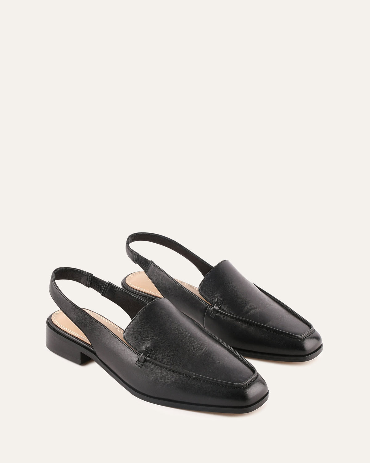 Pair of black leather slingback loafers on a white background