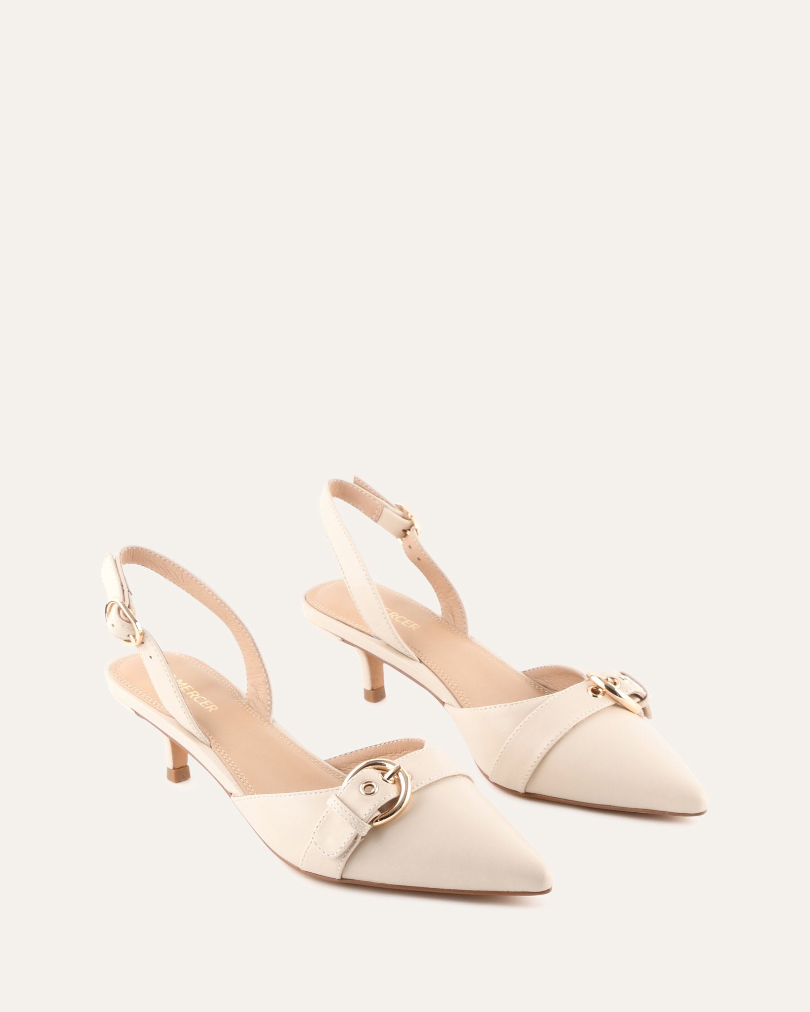 Beige high-heeled shoes with a strap on a white background