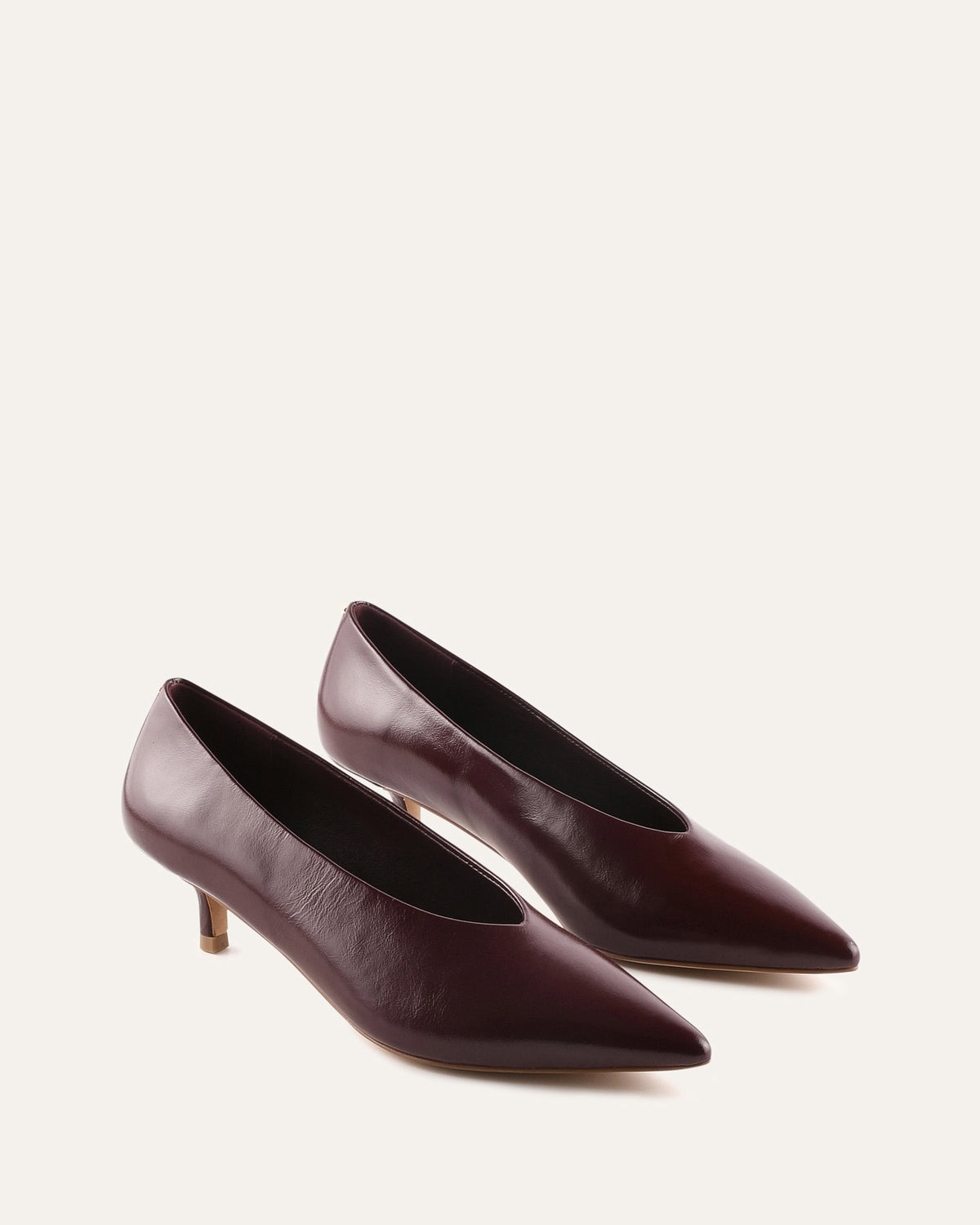 Pair of maroon high-heeled shoes on a light beige background