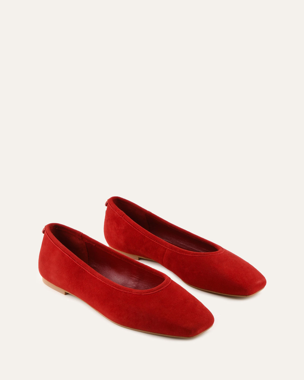 Pair of red suede flats on a white background