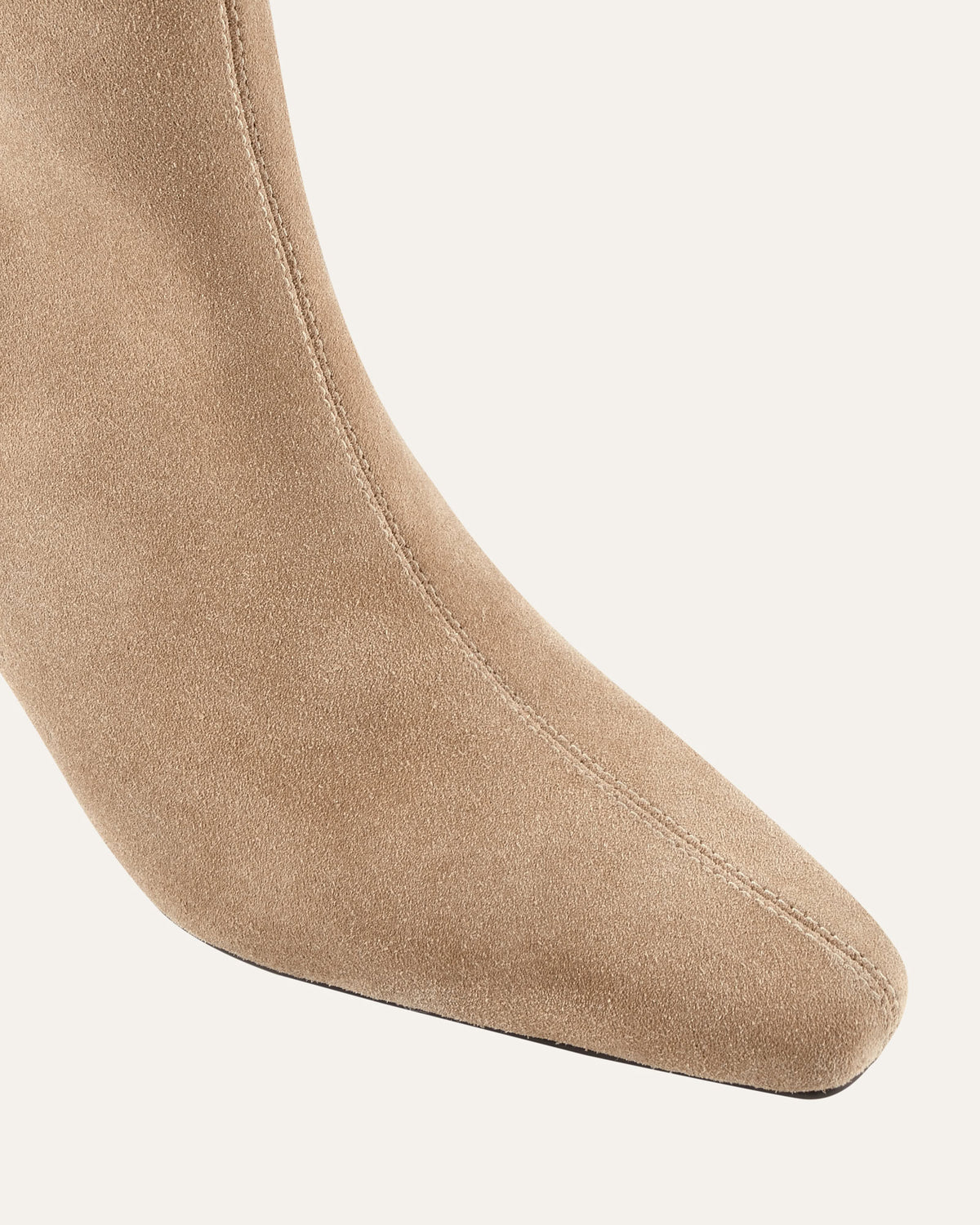 Close-up of a beige suede ankle boot on a light gray background