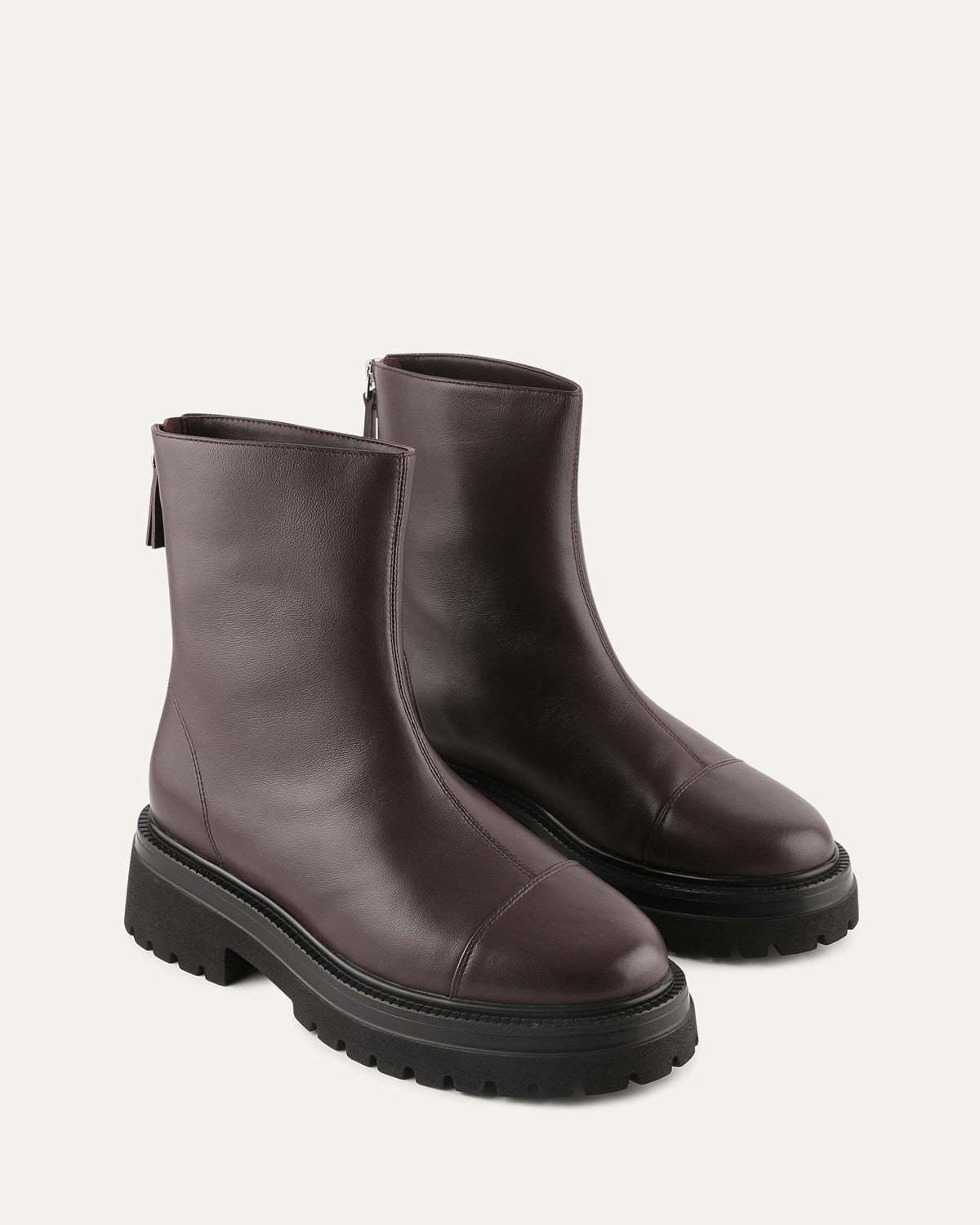 Pair of black leather ankle boots on a light beige background