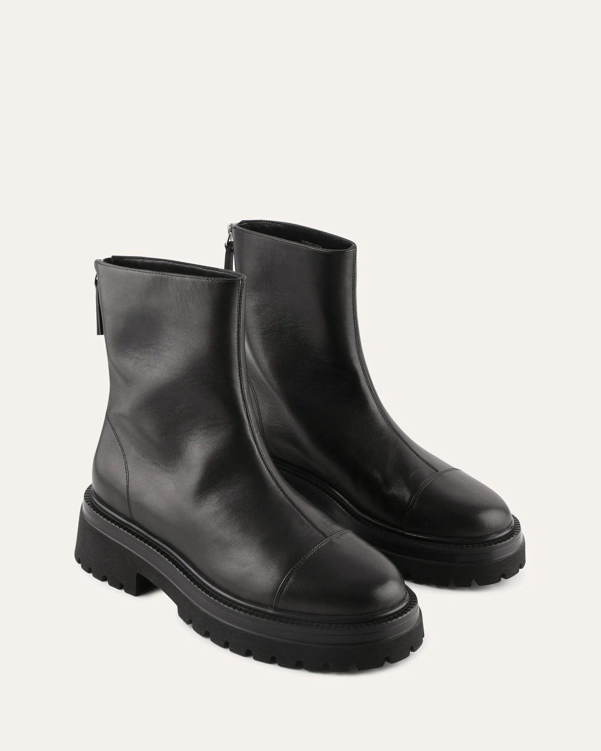 Pair of black leather ankle boots on a light beige background