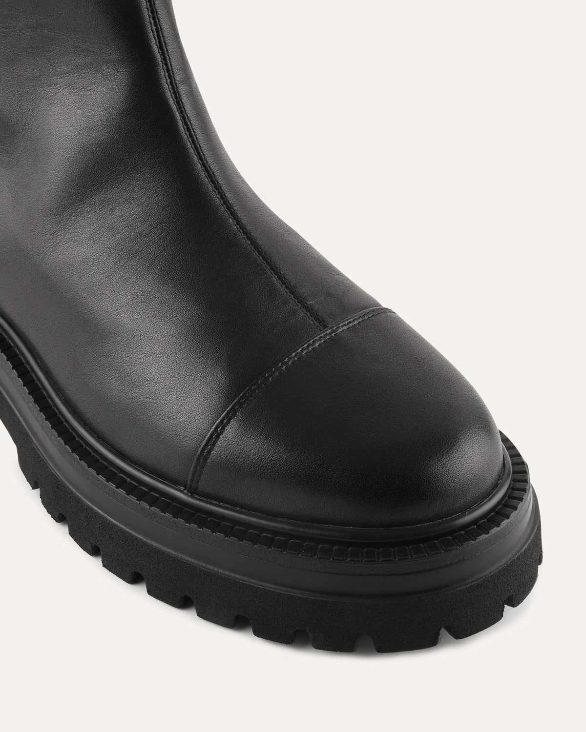 Black leather boot with thick sole on a light gray background
