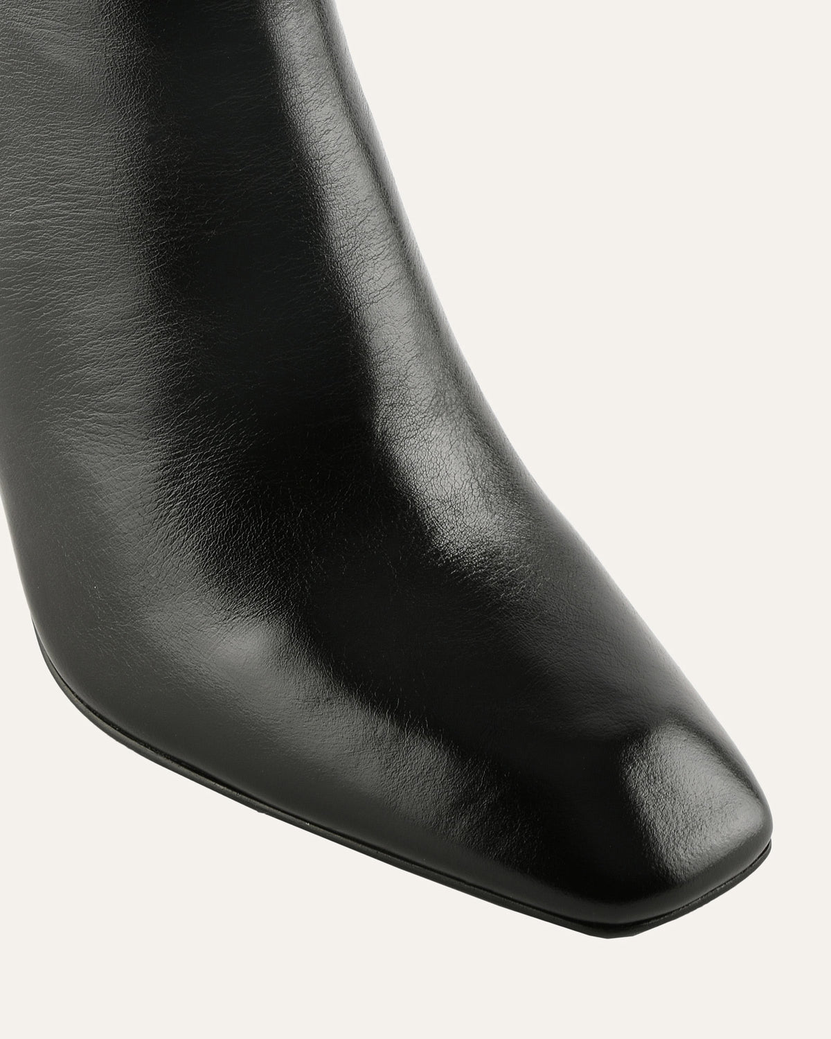 Black leather ankle boot with a square toe on a light gray background