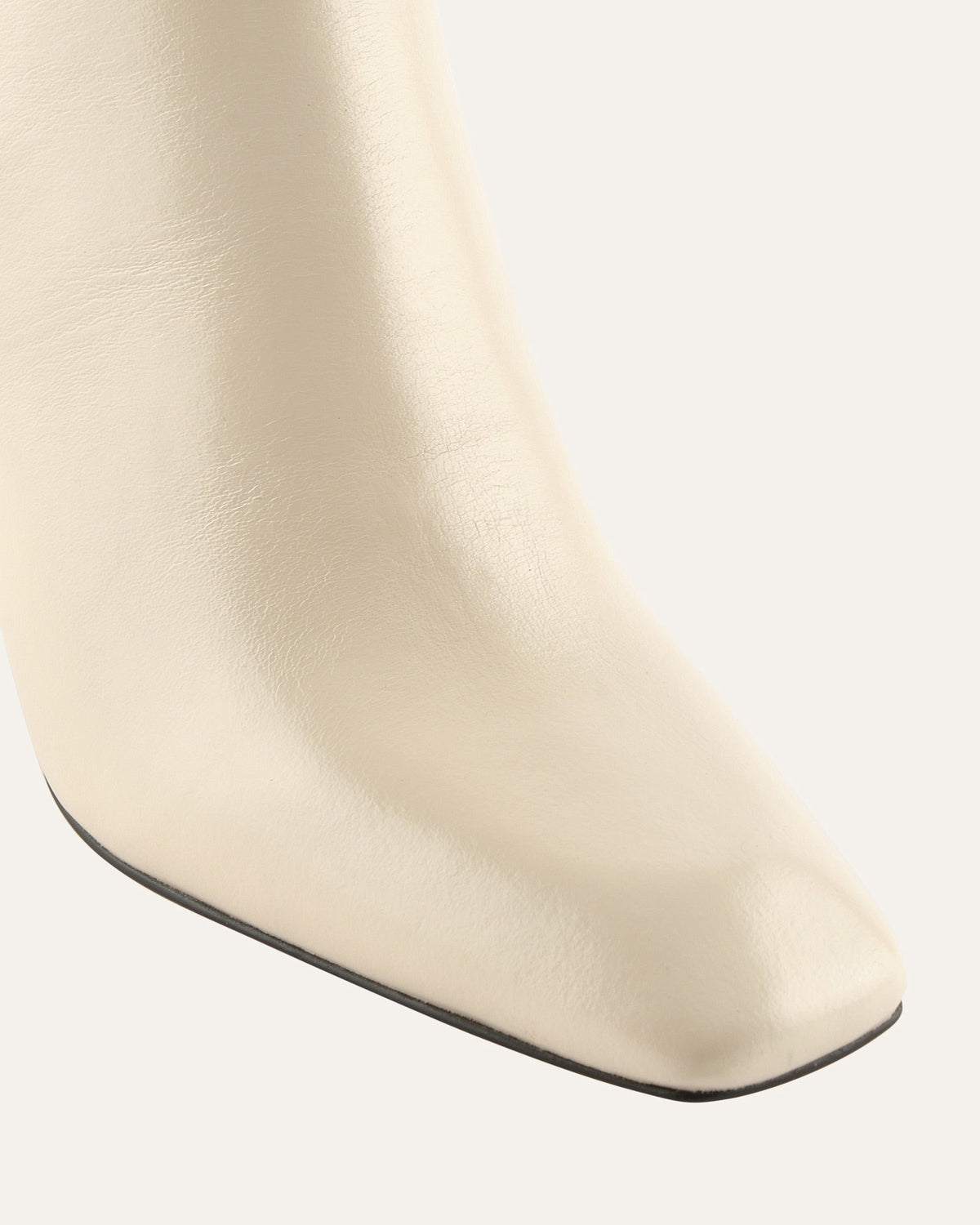 Close-up of a white ankle boot with a slight curve on a light gray background