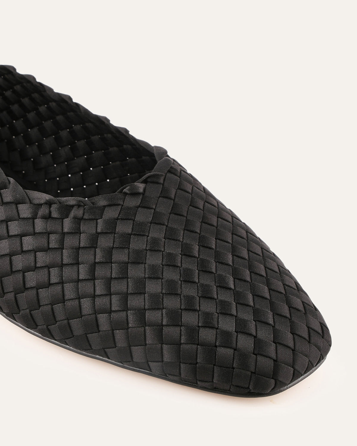 Black woven flat shoe on a white background
