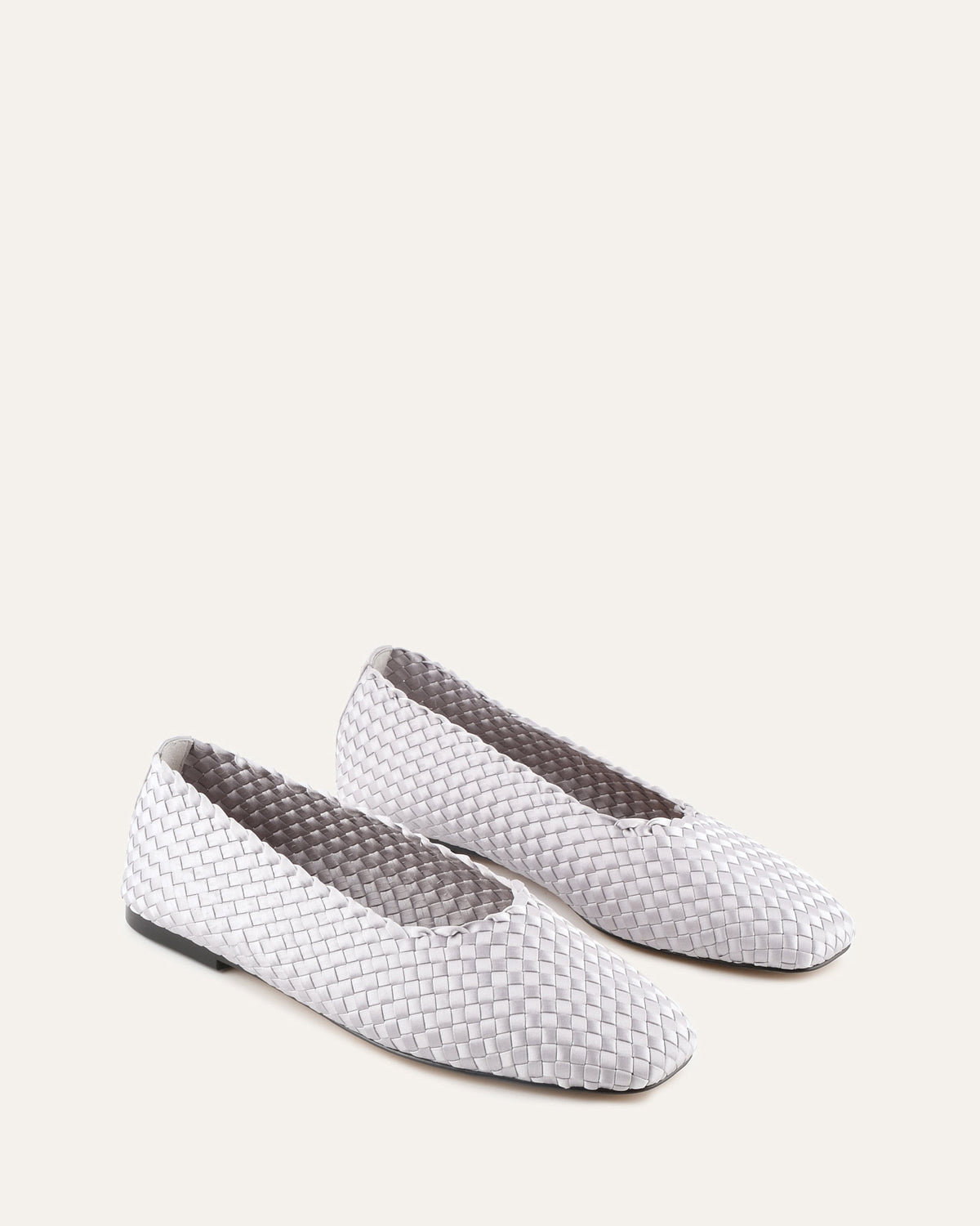 Pair of woven white flats on a light gray background