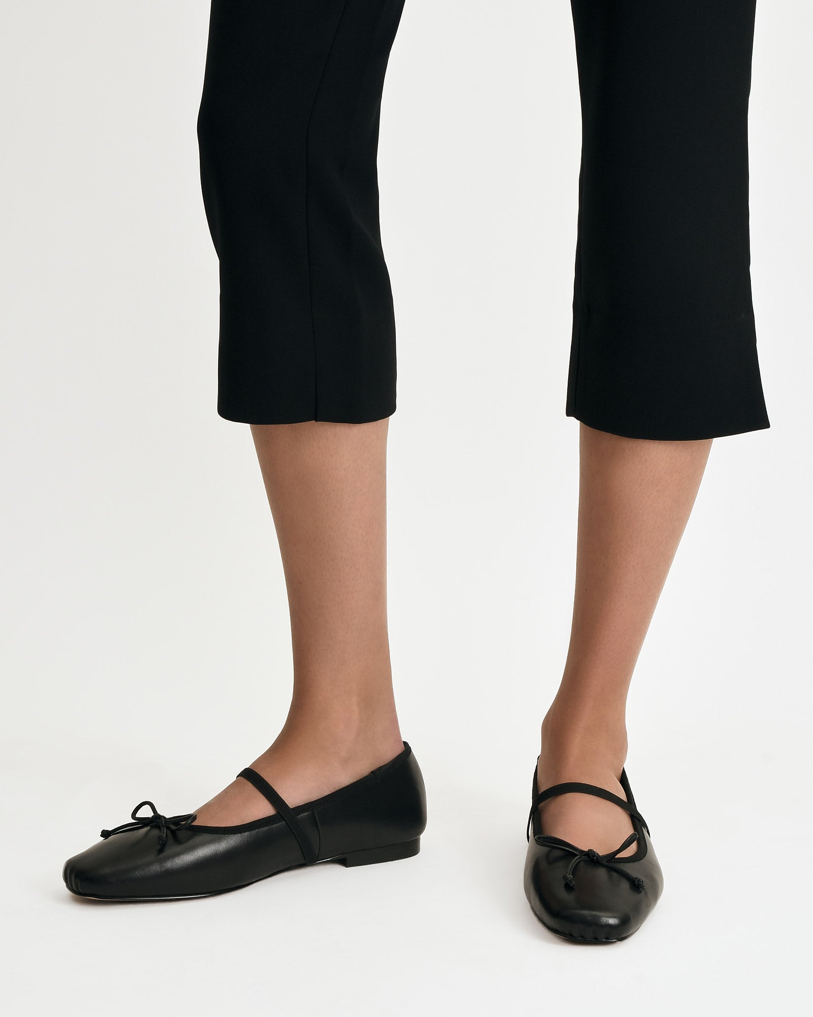 Black leather flat shoe with a strap on a white background