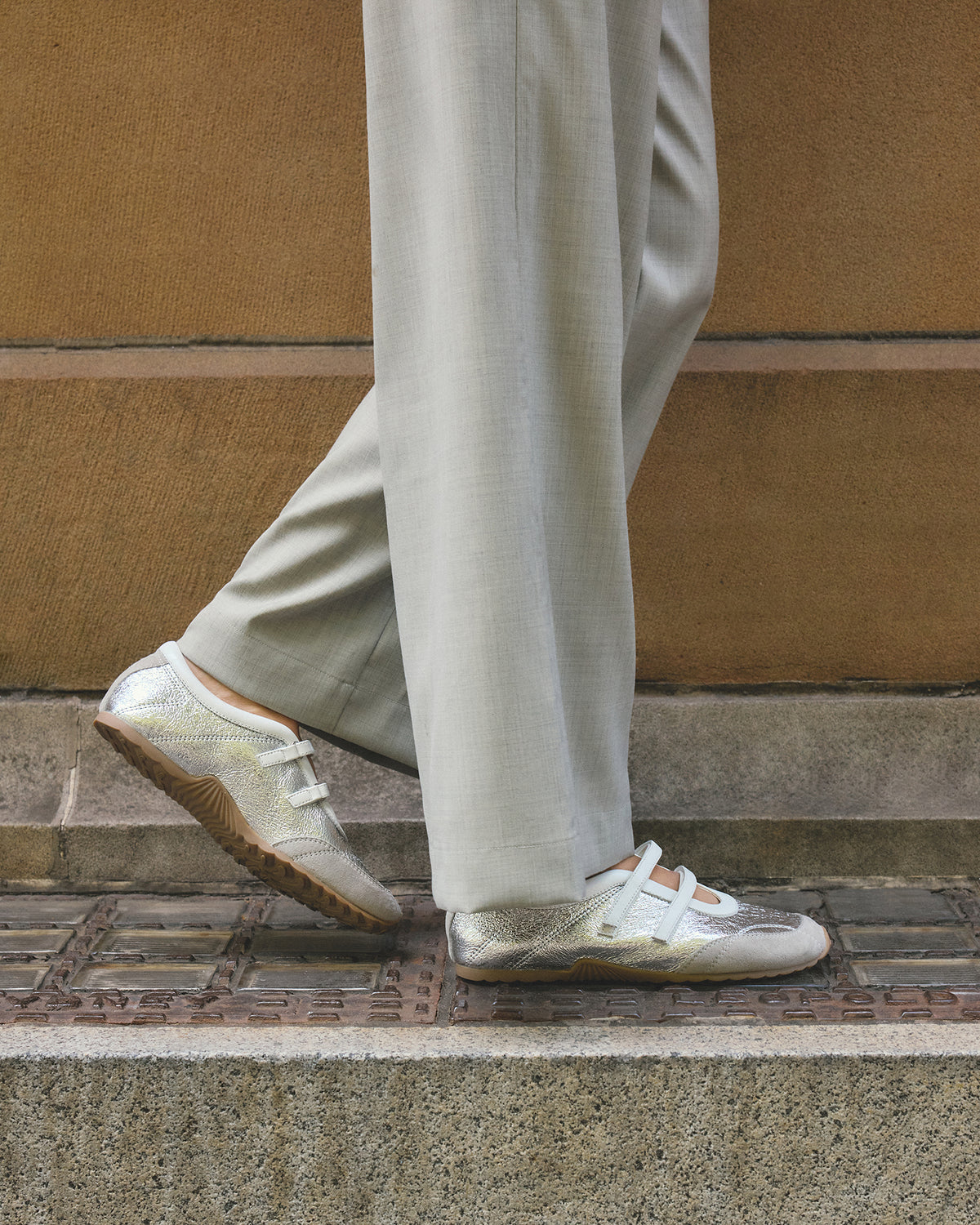 Person wearing light-colored shoes and pants stepping onto a set of stairs.