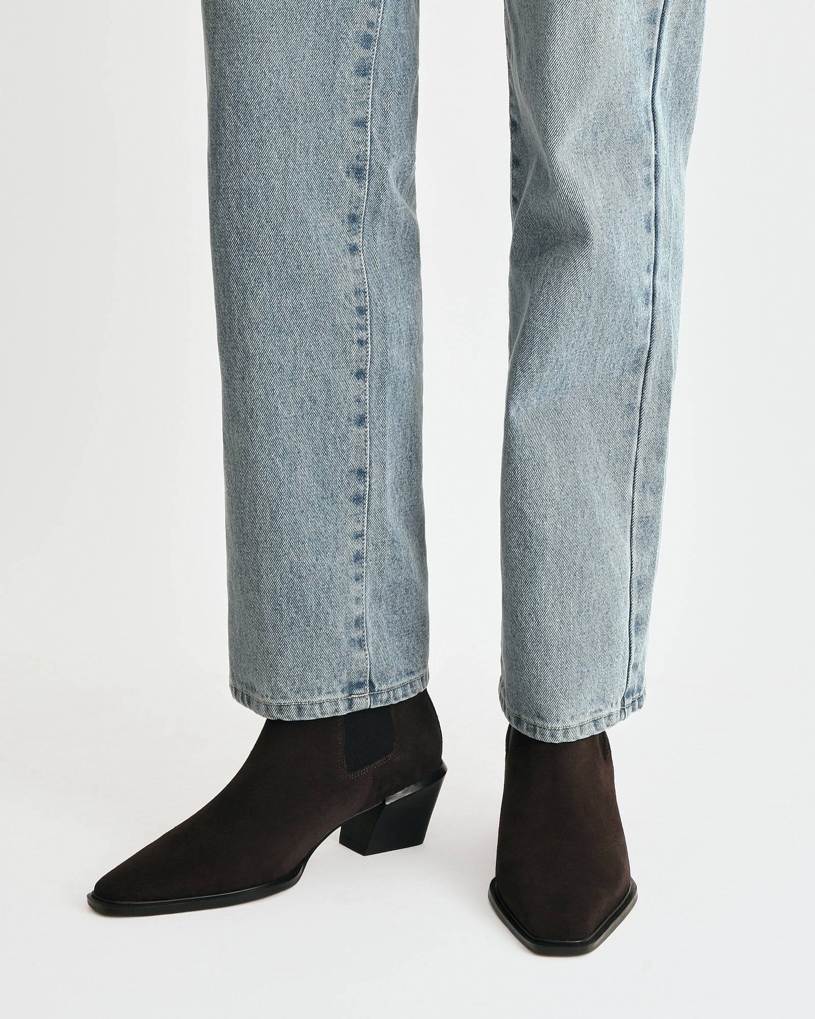 Brown suede ankle boots with a black block heel on a light gray background