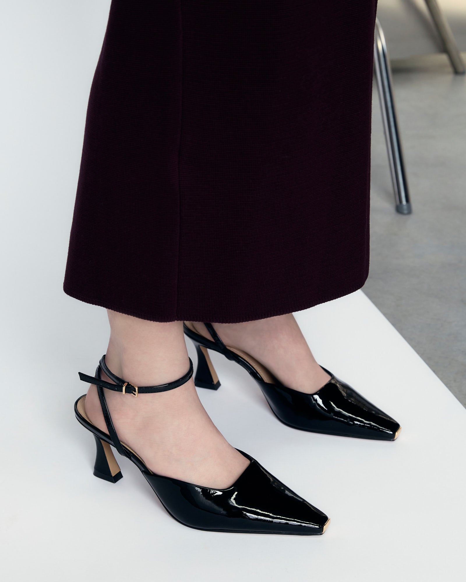 Black high-heeled shoe with a strap on a light gray background
