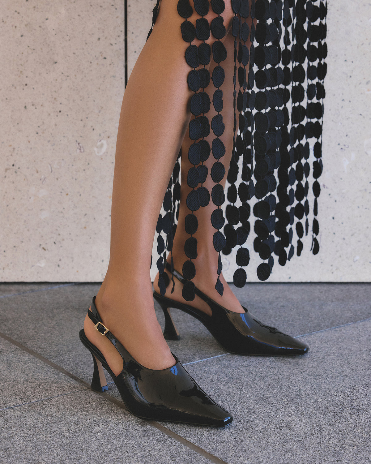 Black high-heeled shoes worn with a black dress.