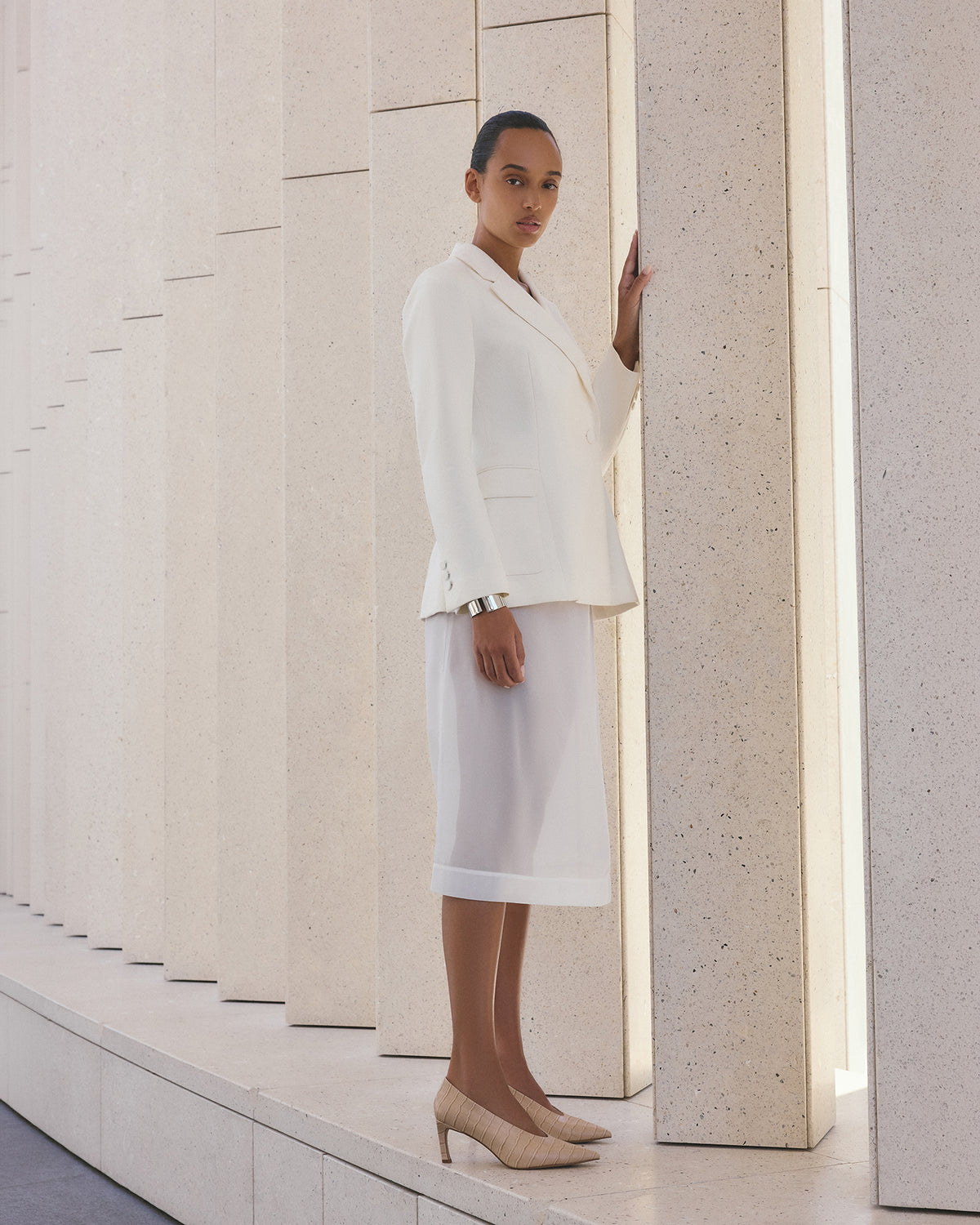 Woman in a white outfit standing between two columns in a minimalistic setting