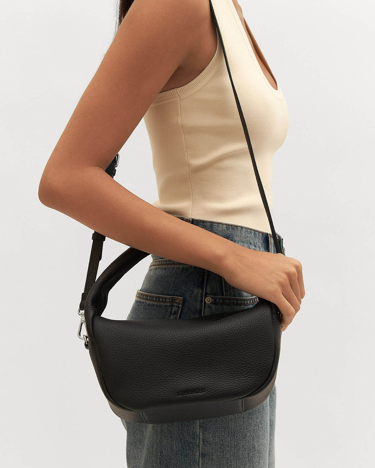 Person wearing a black shoulder bag on a plain background