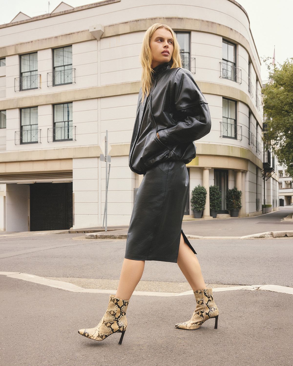Woman in black leather outfit walking on a city street
