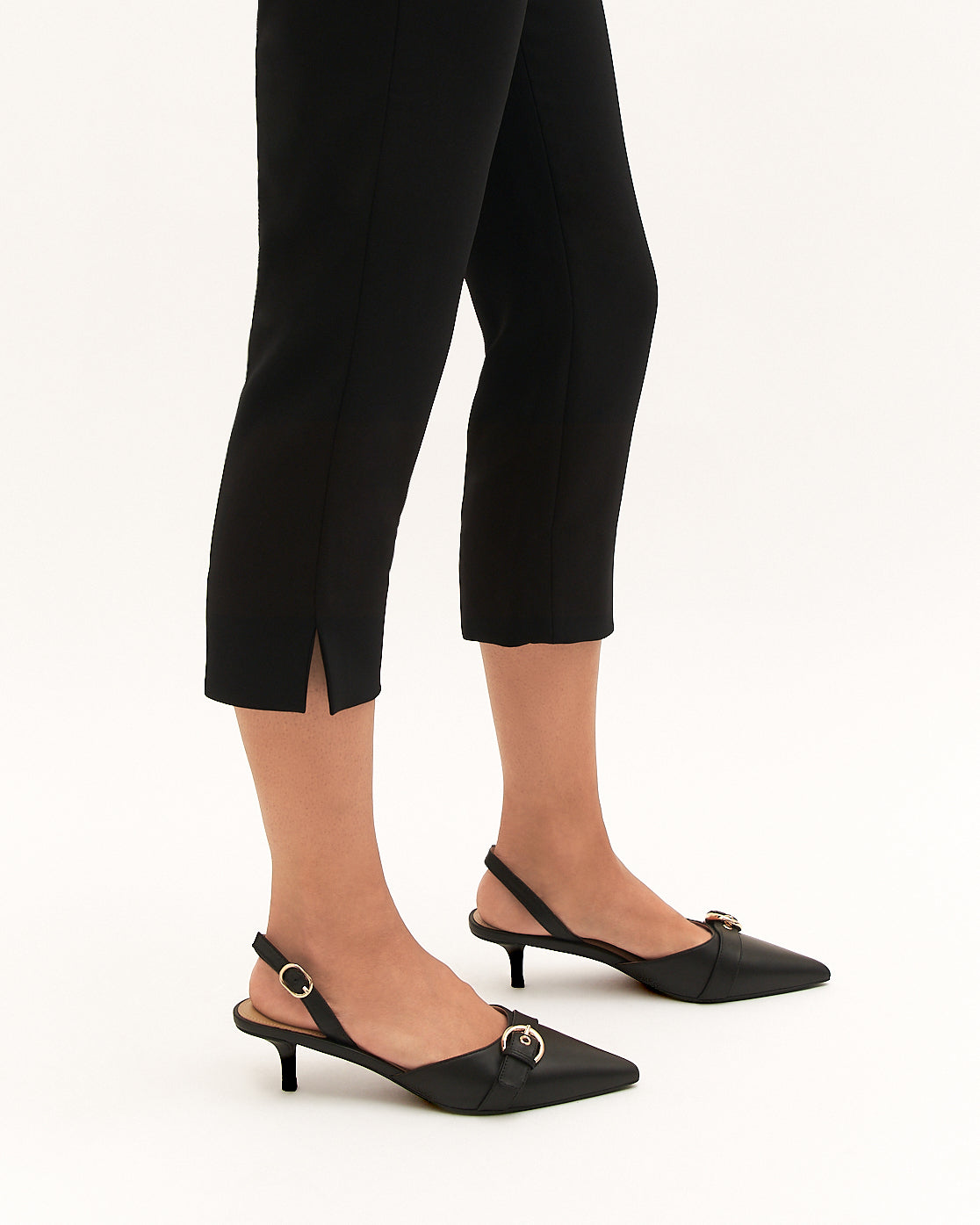 Black kitten heel shoes worn with black pants on a white background
