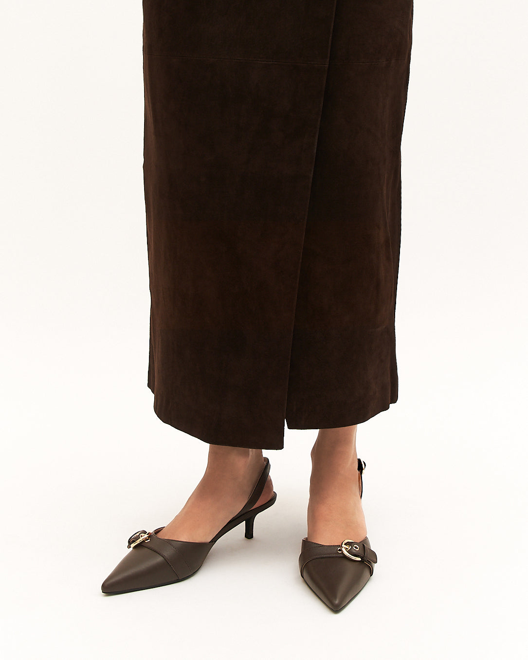 Brown suede shoes worn with brown skirt on a white background