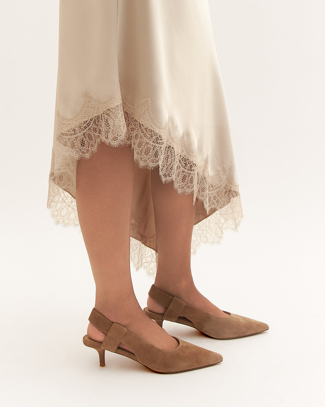 Beige high-low dress with lace trim and brown high-heeled shoes on a white background