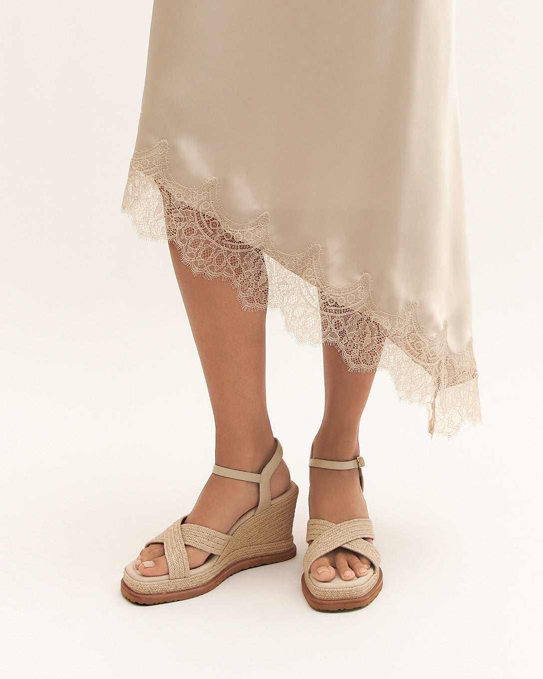 Person wearing beige sandals with a white background