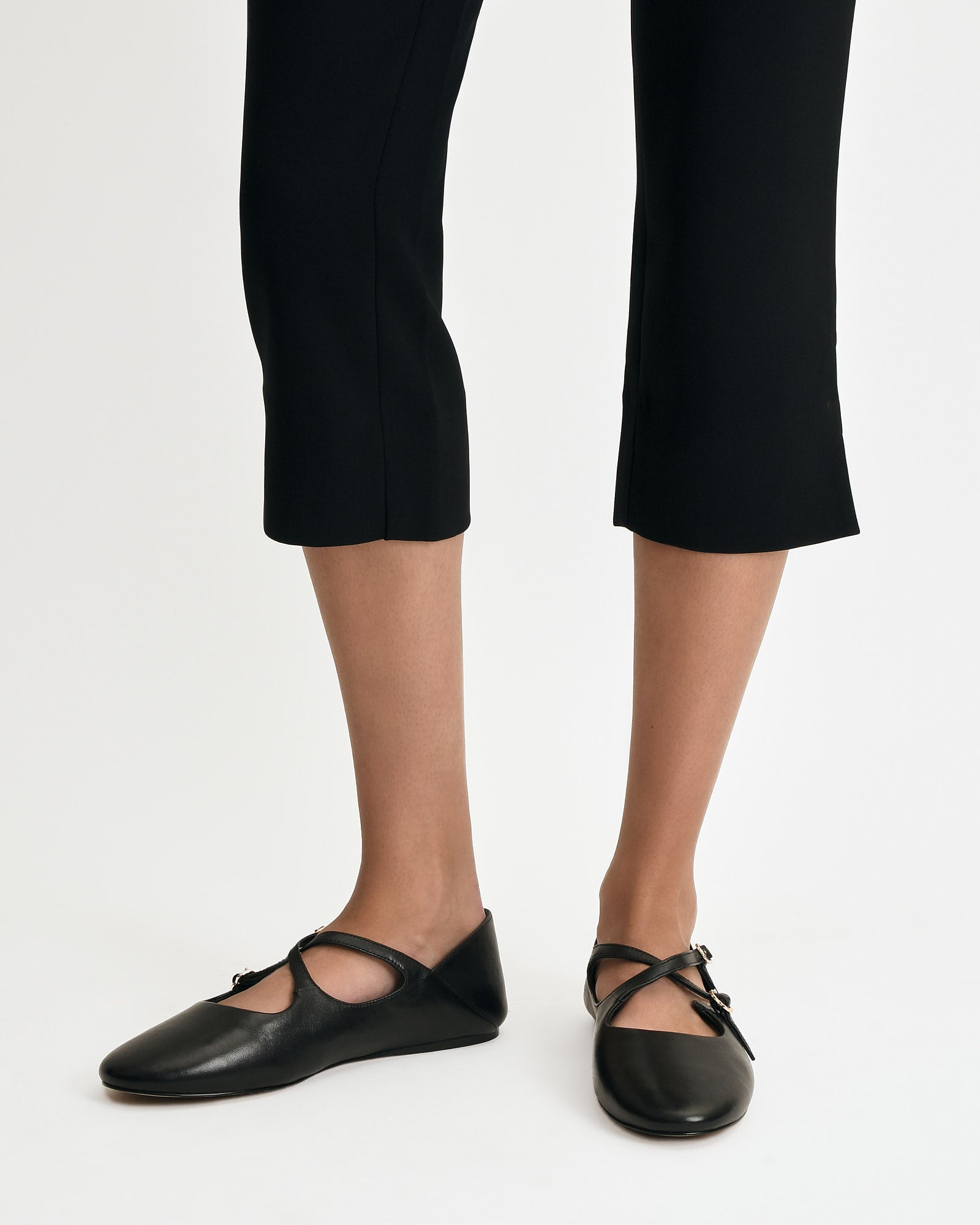 Black flat shoe with a strap on a white background
