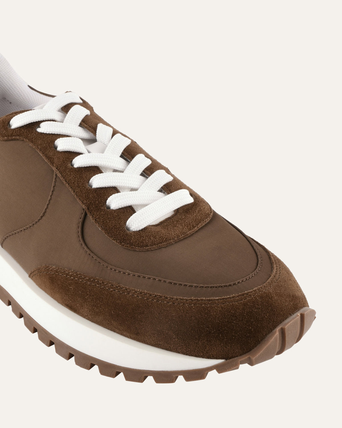 Brown sneaker with white laces on a light gray background