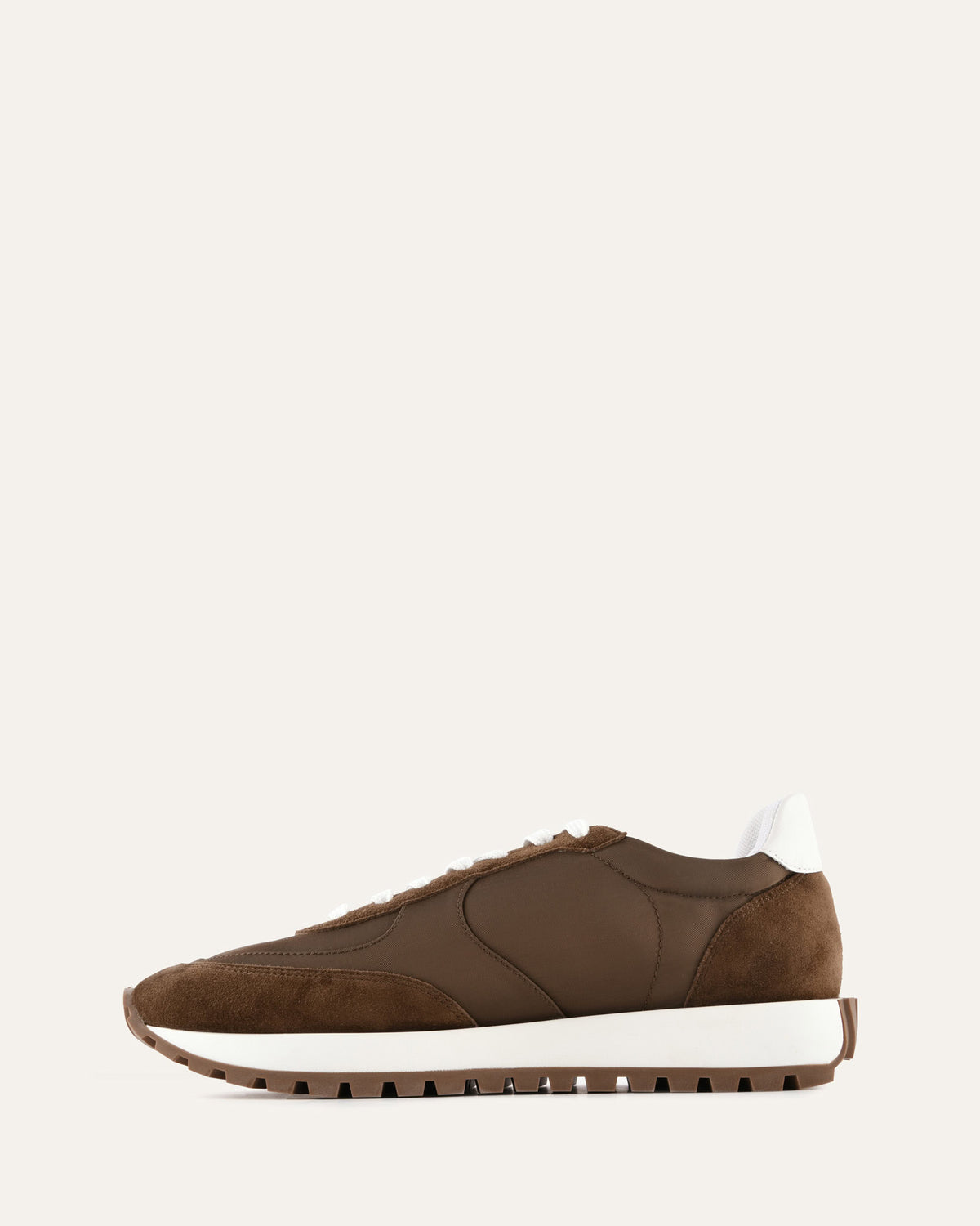Brown sneaker with white sole on a light beige background