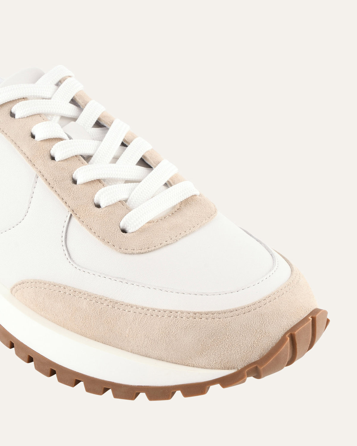 White and beige sneaker with brown sole on a light gray background