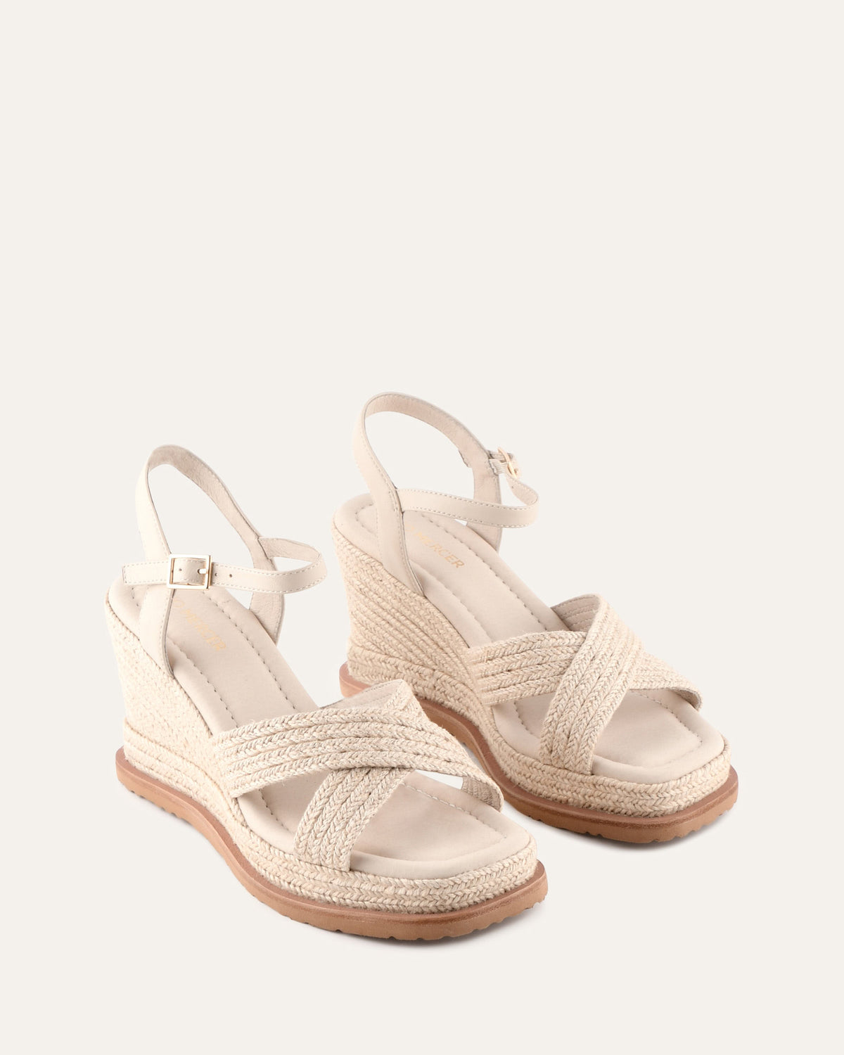 Pair of beige sandals with espadrille sole on a white background