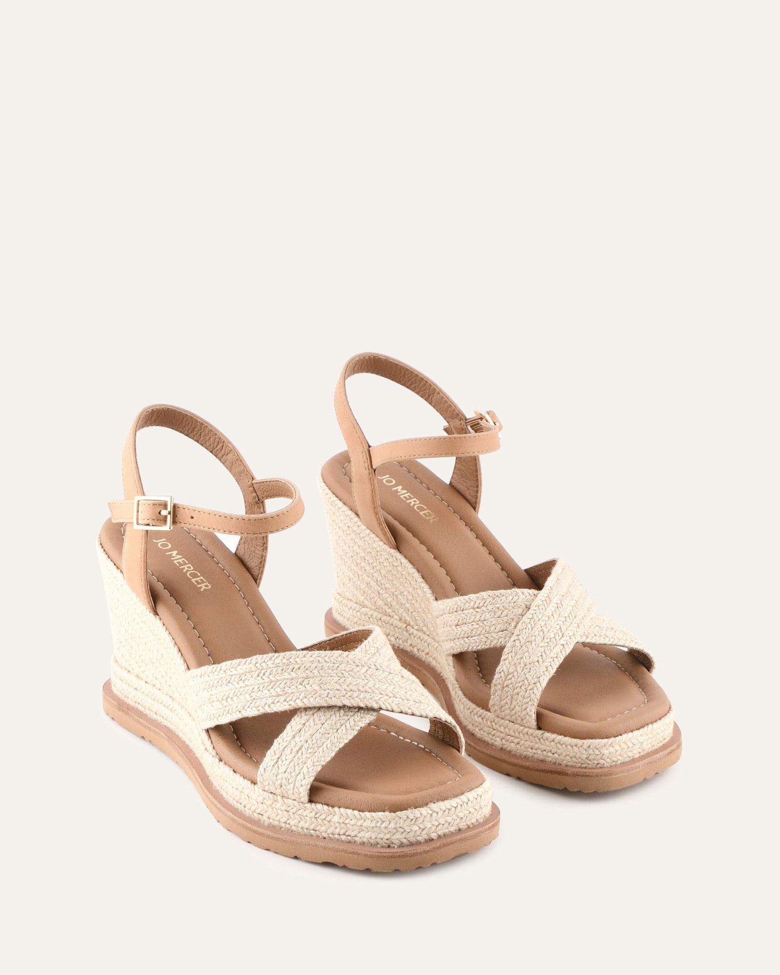 Beige wedge sandal with criss-cross straps on a light beige background