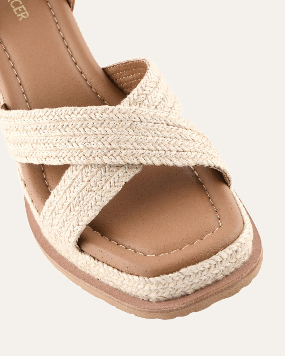 Beige sandal with woven straps on a light gray background