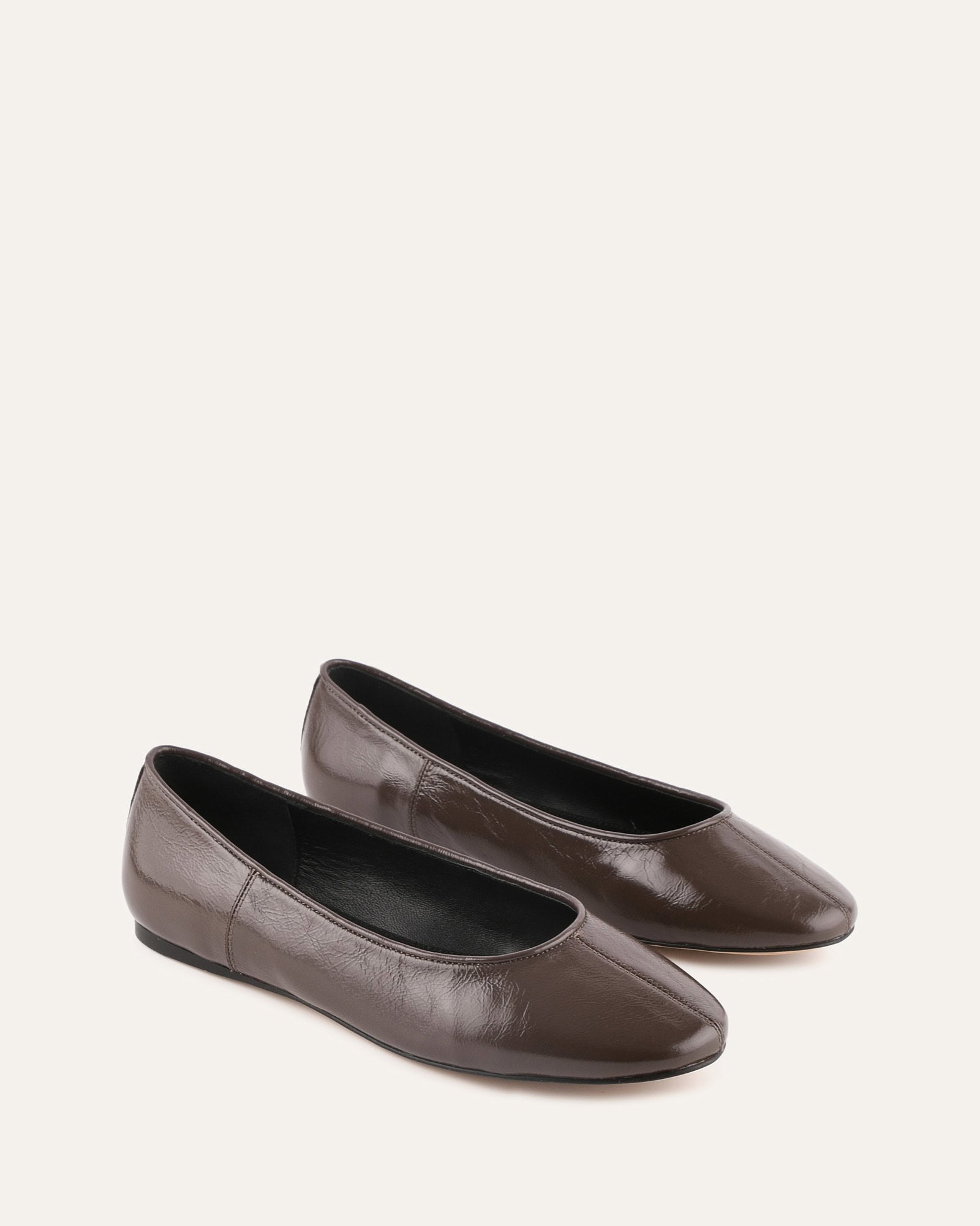 Brown leather flat shoe on a light beige background