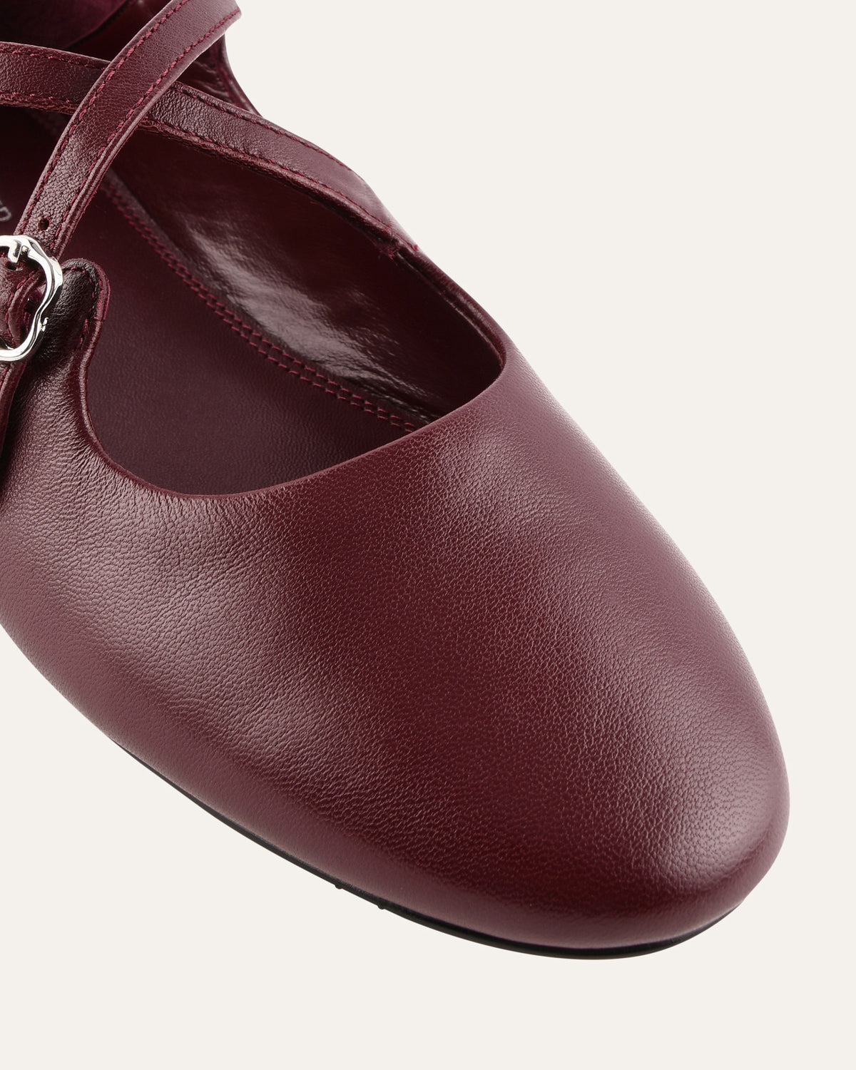 Maroon ballet shoe with a strap on a white background