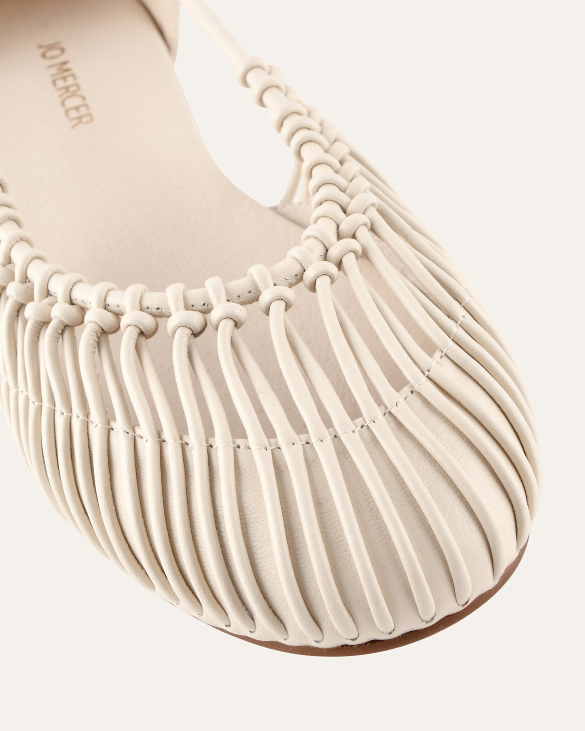 Close-up of a beige ballet shoe with 'Jo Mercer' branding on a white background
