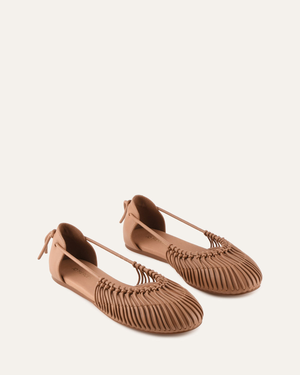 Pair of brown flat shoes with woven design on a white background